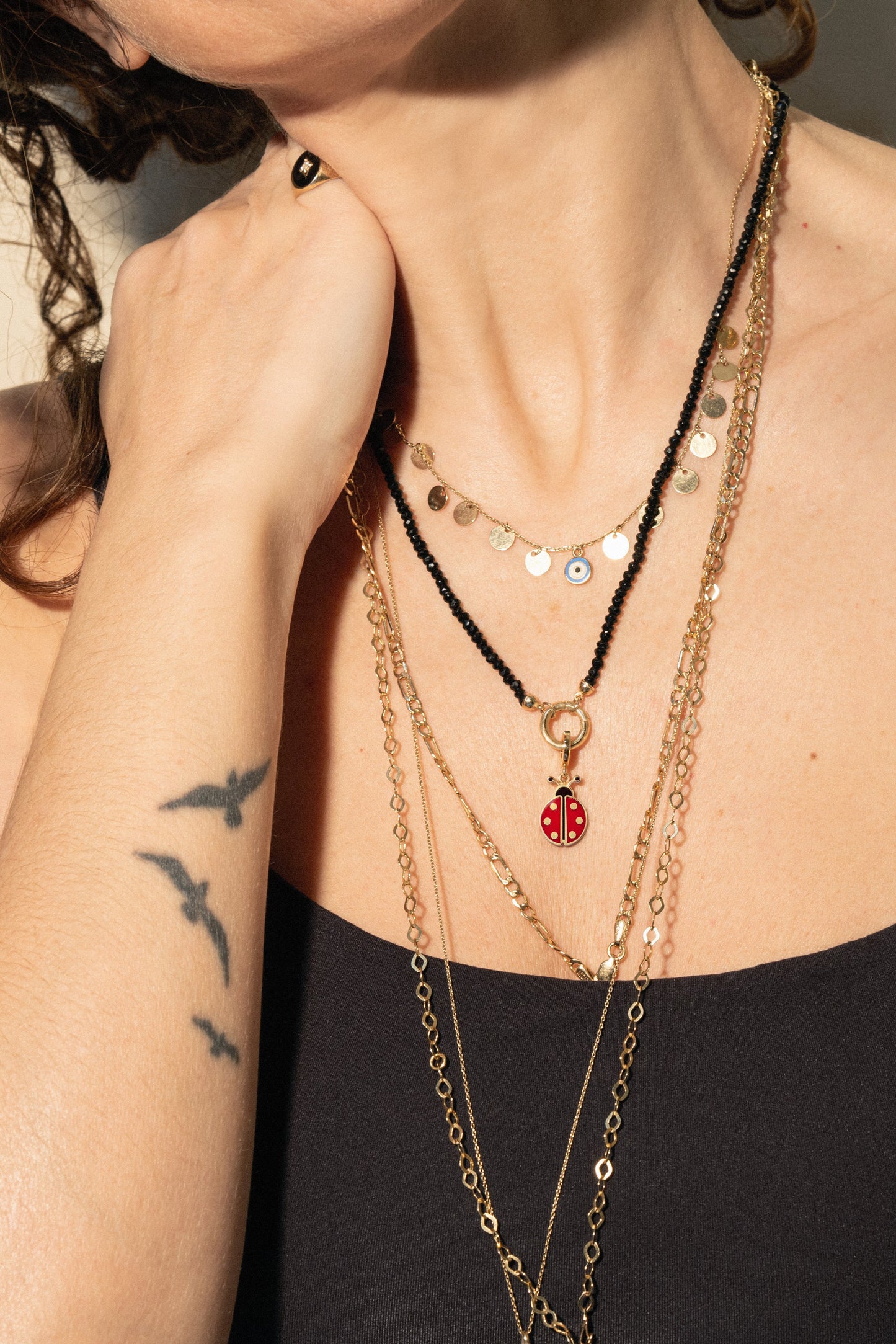 A lifestyle photo of the Noir Elegance Lucky Ladybird Charm Necklace, layered on a model, blending playful luxury with everyday elegance.