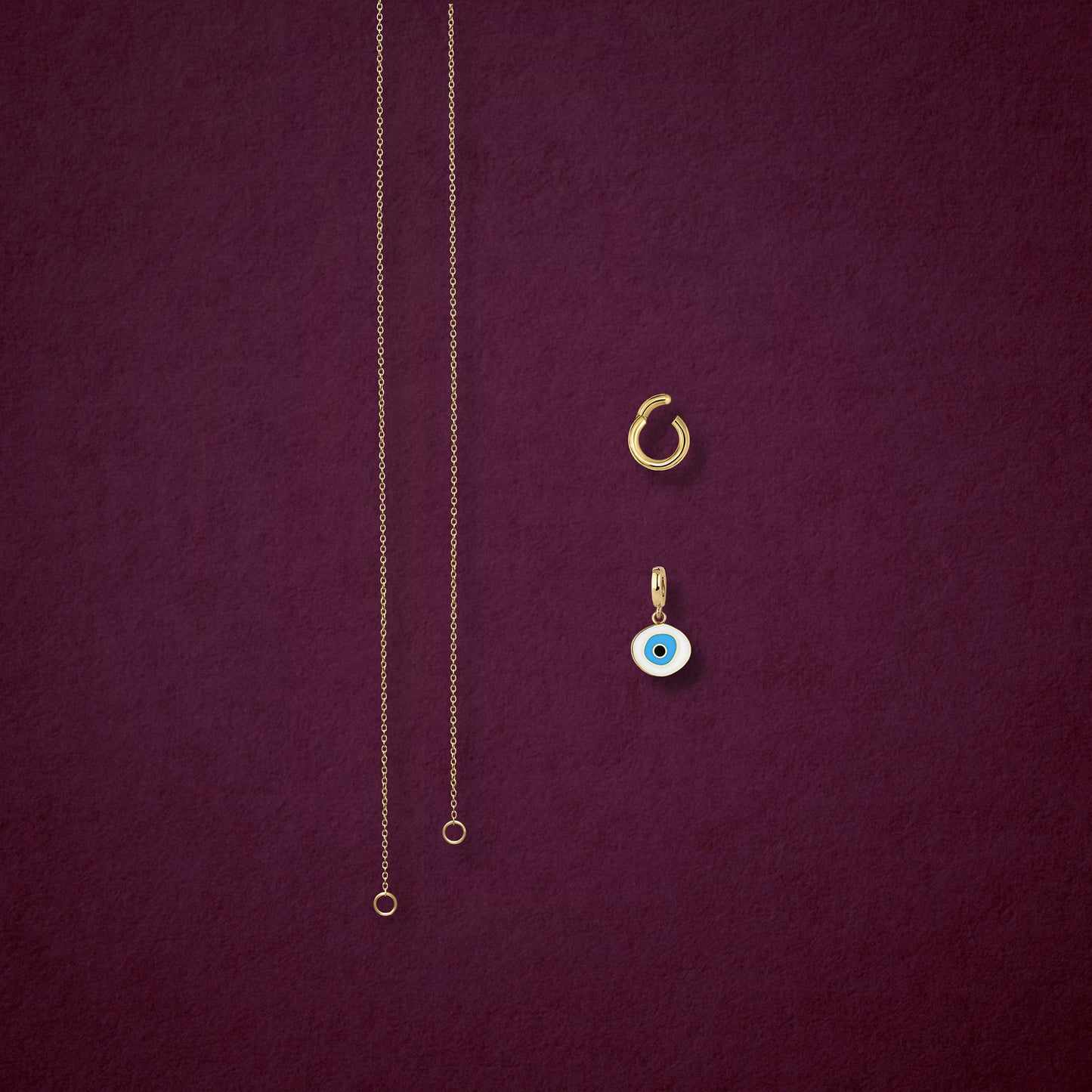 Azure Organic Evil Eye Charm, Golden Link Charm Holder, and the Golden Grace cable chain necklace displayed separately on a soft pink background to show styling options.