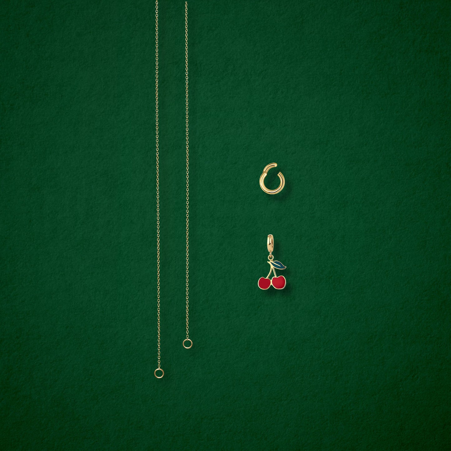Separated components of the Golden Grace Cherry on Top Charm Necklace, including 14K solid gold cable chain, golden link charm holder, and cherry on top charm with red enamel by whywhy NYC.