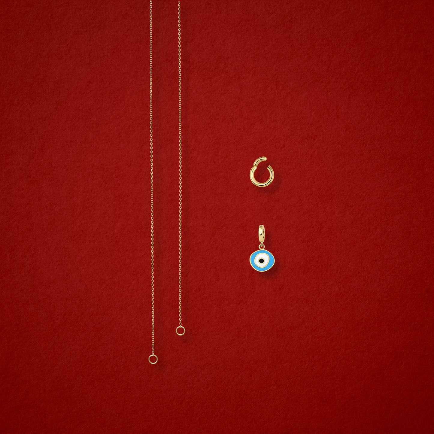 Sky Organic Evil Eye Charm, Golden Link Charm Holder, and the Golden Grace cable chain necklace displayed separately on a red background to show styling options.