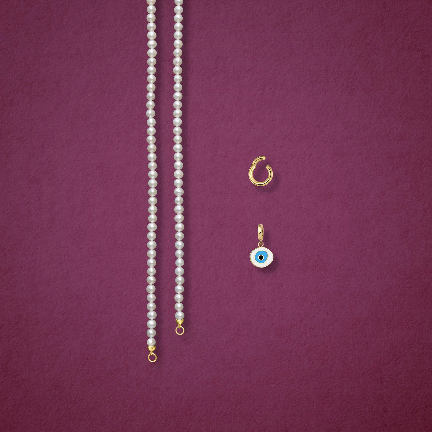 Azure Organic Evil Eye Charm, Golden Link Charm Holder, and the Lustrous Pearl necklace displayed separately on a soft pink background to show styling options.
