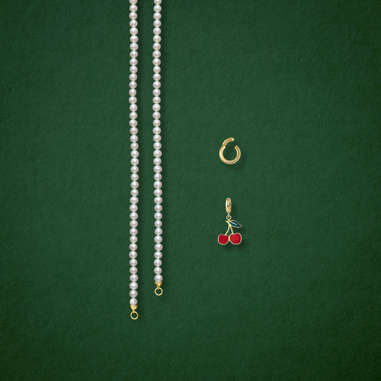 Separated components of the Lustrous Pearl Cherry on Top Charm Necklace, including pearl necklace, charm holder, and cherry on top charm in 14K solid gold by whywhy NYC.