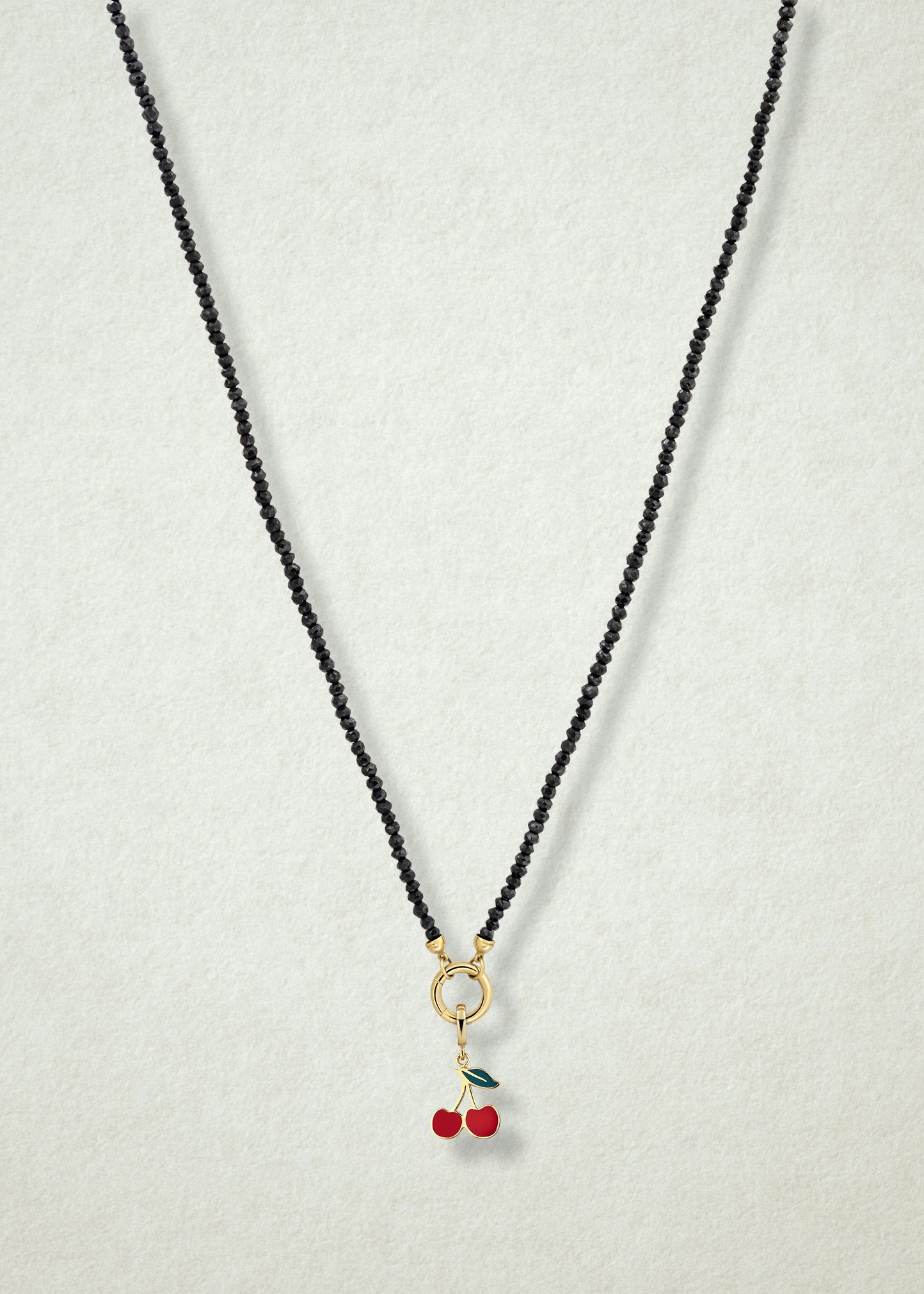 Noir Elegance Cherry on Top Charm Necklace in full view, showcasing faceted black spinel beads, a golden link charm holder, and cherry on top charm with red enamel by whywhy NYC.