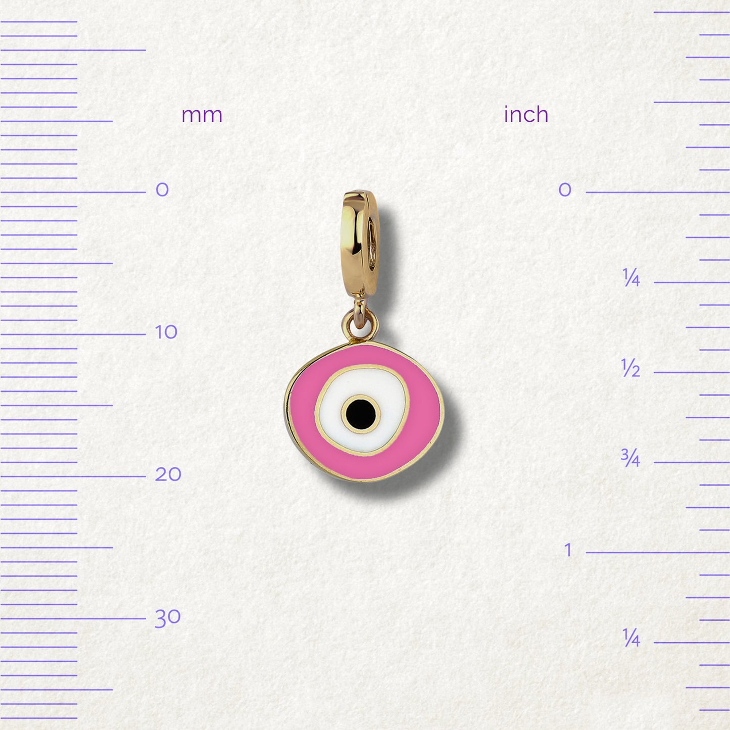 Blush Organic Evil Eye Charm with pink, white, and black enamel displayed beside measurement markers on a soft light background to show its size.