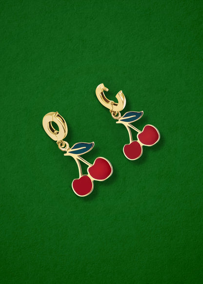 Cherry on Top Charm showing both open and closed views of the 14K solid gold clip, with rich red enamel detailing, displayed on a green background.