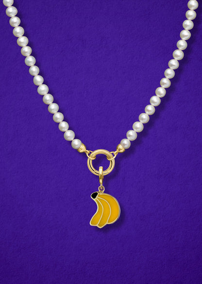 Close-up of the Banana Bliss Charm paired with the Lustrous Pearl Charm Necklace by whywhy NYC, featuring 14K solid gold and freshwater pearls for a bold yet elegant style.