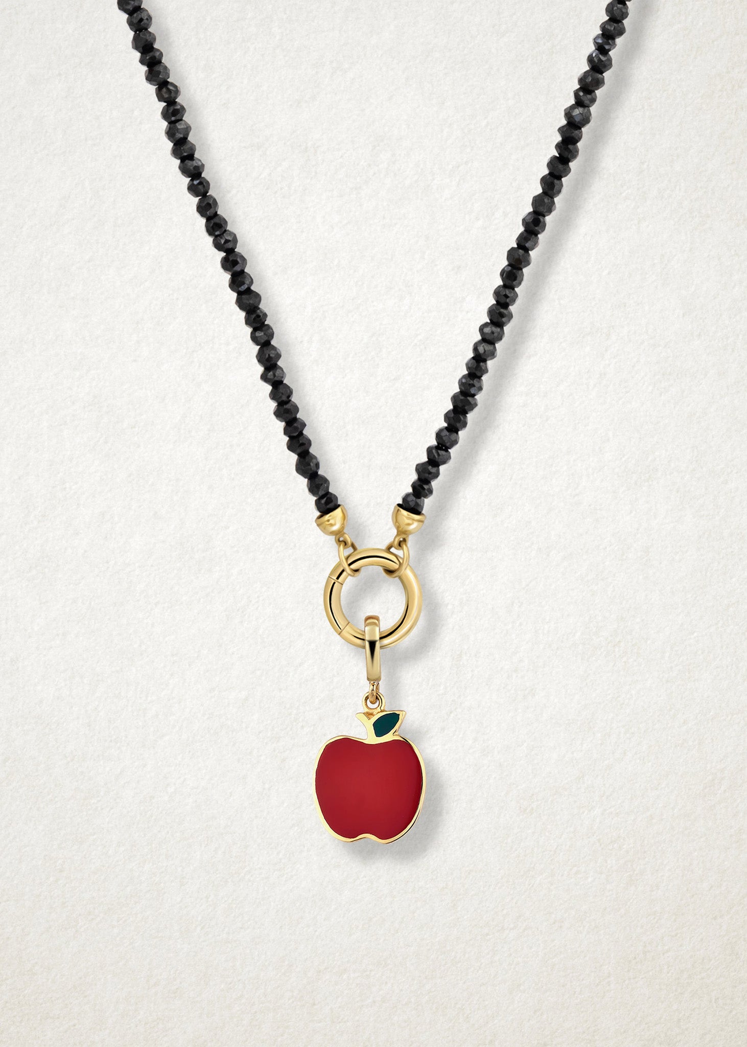 Close-up of the Golden Apple Charm paired with the Noir Elegance Charm Necklace by whywhy NYC, featuring black spinel and 14K solid gold for a striking and sophisticated design.