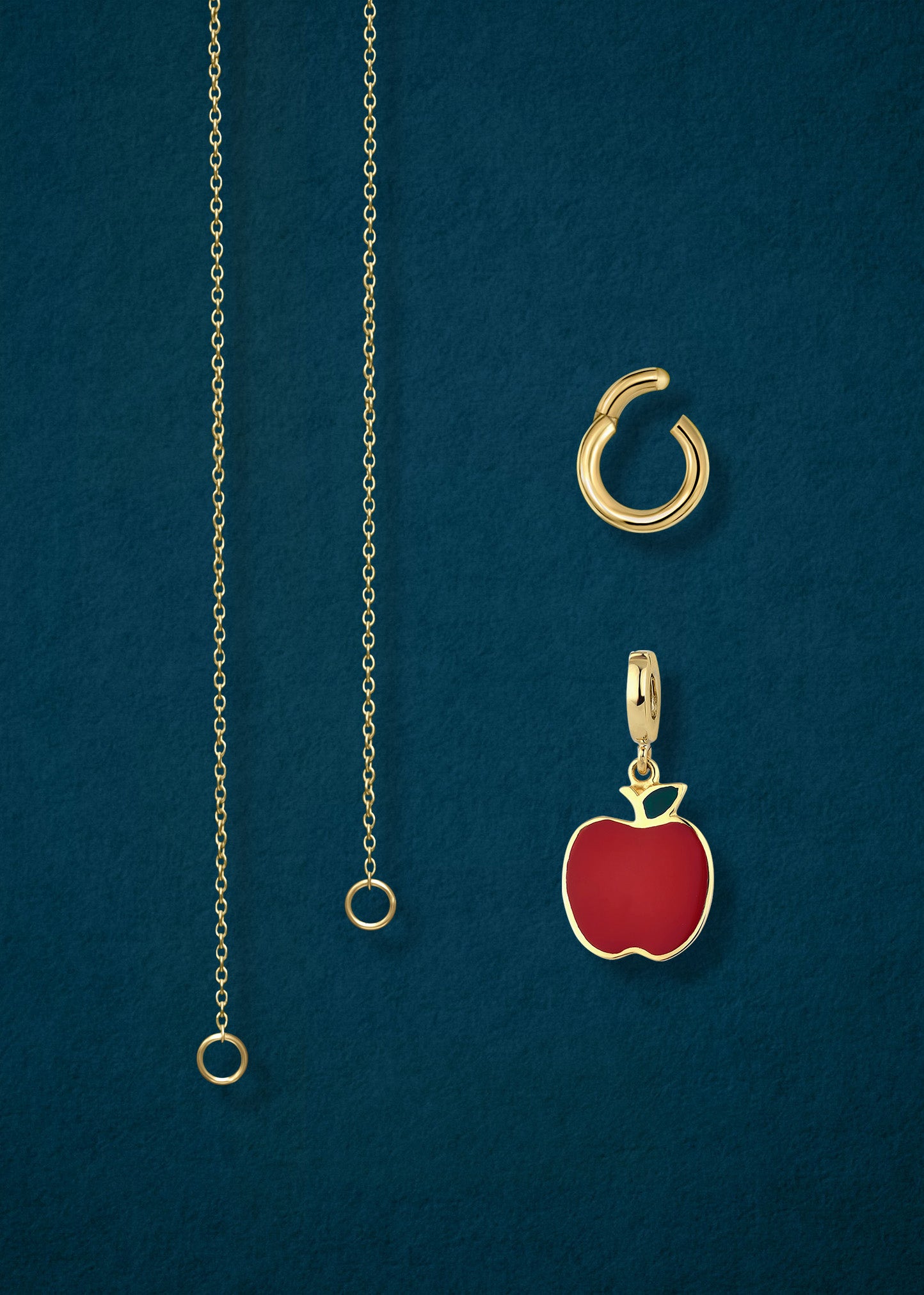 Close-up of the separated Golden Grace Apple Charm Necklace components: 14K solid gold cable chain, golden link charm holder, and golden apple of NYC charm with red enamel by whywhy NYC.