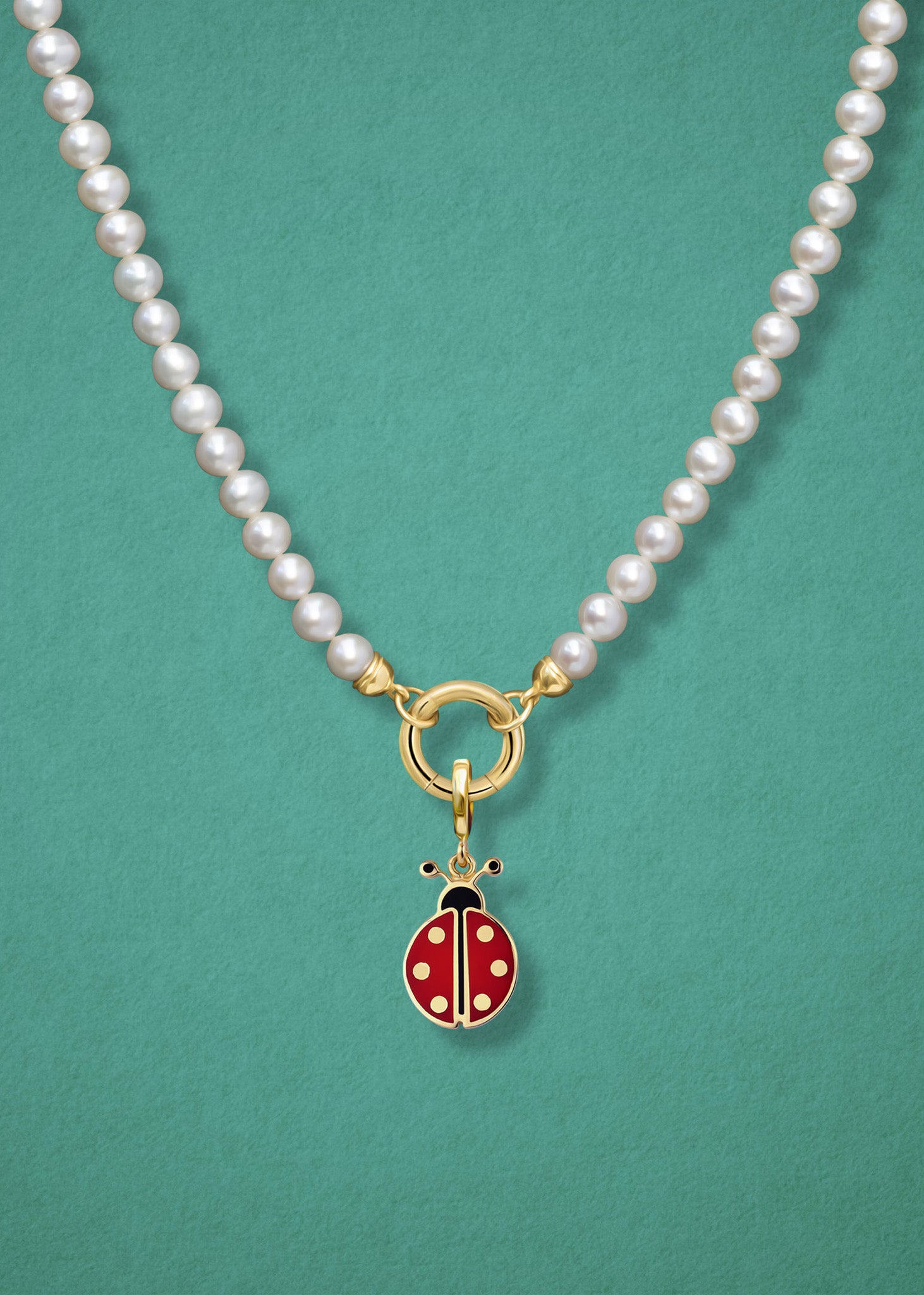 Close-up of the Lucky Ladybird Charm paired with the Lustrous Pearl Charm Necklace by whywhy NYC, featuring 14K solid gold and freshwater pearls for a whimsical yet elegant look.