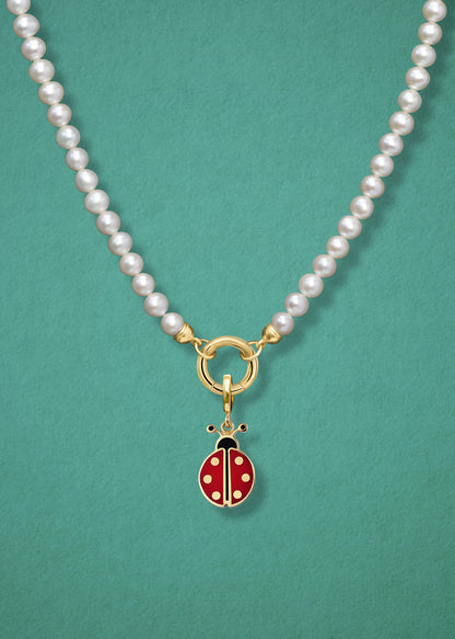 Close-up of the Lucky Ladybird Charm paired with the Lustrous Pearl Charm Necklace by whywhy NYC, featuring 14K solid gold and freshwater pearls for a whimsical yet elegant look.