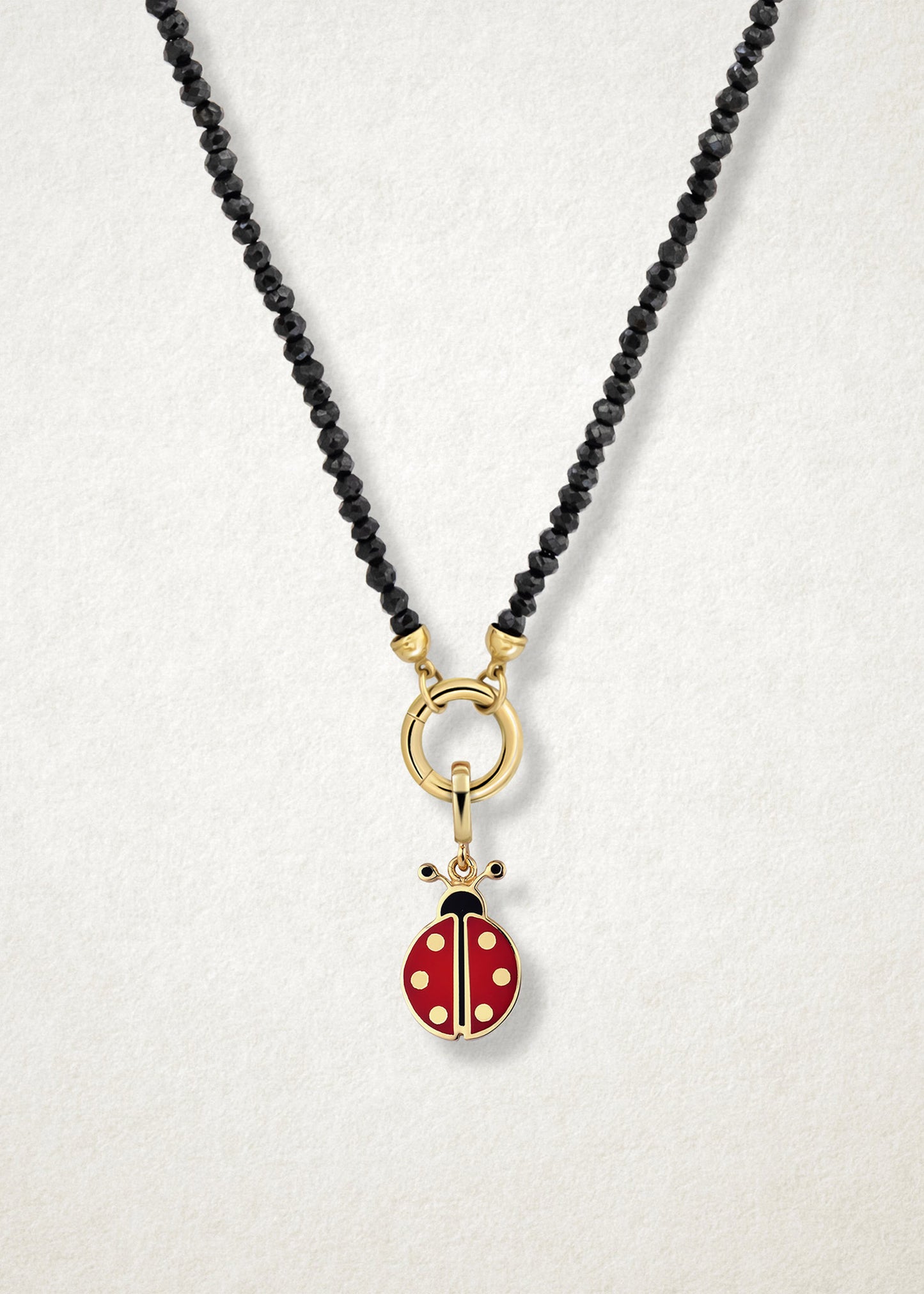 Close-up of the Lucky Ladybird Charm paired with the Noir Elegance Charm Necklace by whywhy NYC, featuring black spinel and 14K solid gold for a bold and playful combination.