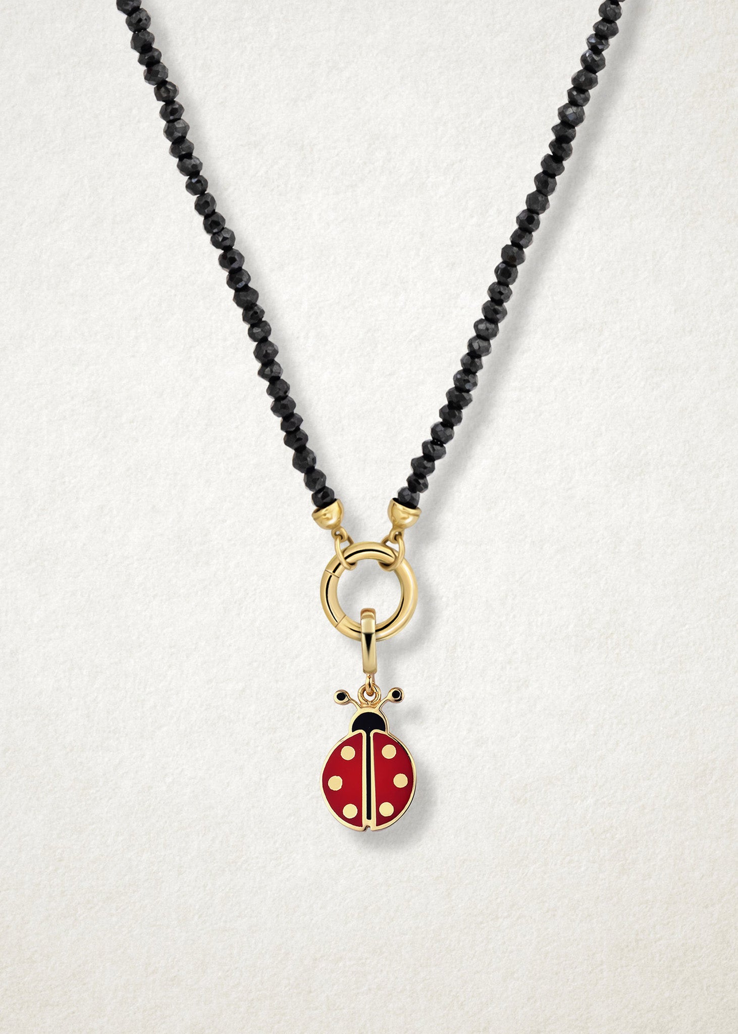 Close-up of the Lucky Ladybird Charm paired with the Noir Elegance Charm Necklace by whywhy NYC, featuring black spinel and 14K solid gold for a bold and playful combination.