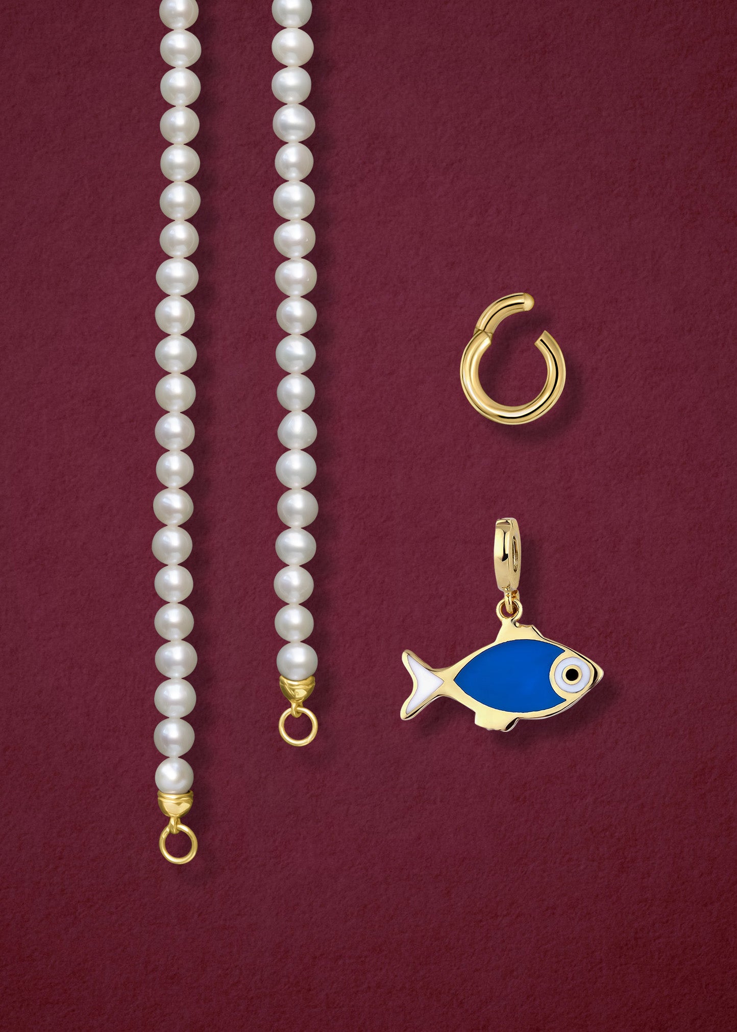 Close-up of the separated Lustrous Pearl Fishy Wishes Charm Necklace components: pearl necklace, golden link charm holder, and fishy wishes charm in 14K solid gold by whywhy NYC.