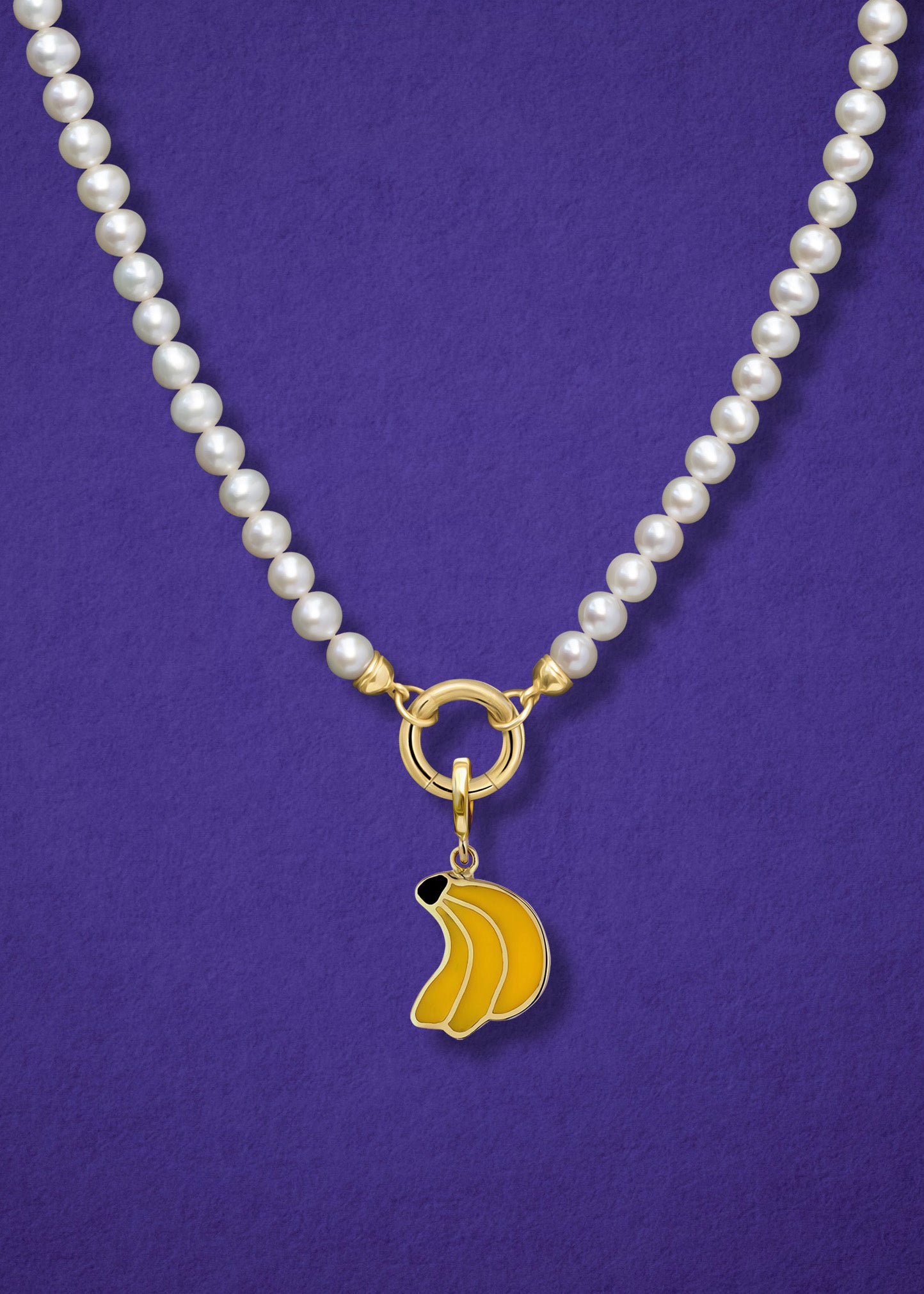 Close-up of the Lustrous Pearl Banana Bliss Charm Necklace, featuring freshwater pearls, a golden link charm holder, and a banana bliss charm in 14K solid gold by whywhy NYC.