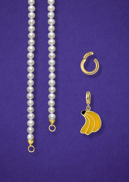 Close-up of the separated Lustrous Pearl Banana Bliss Charm Necklace components: pearl necklace, golden link charm holder, and banana bliss charm in 14K solid gold by whywhy NYC.