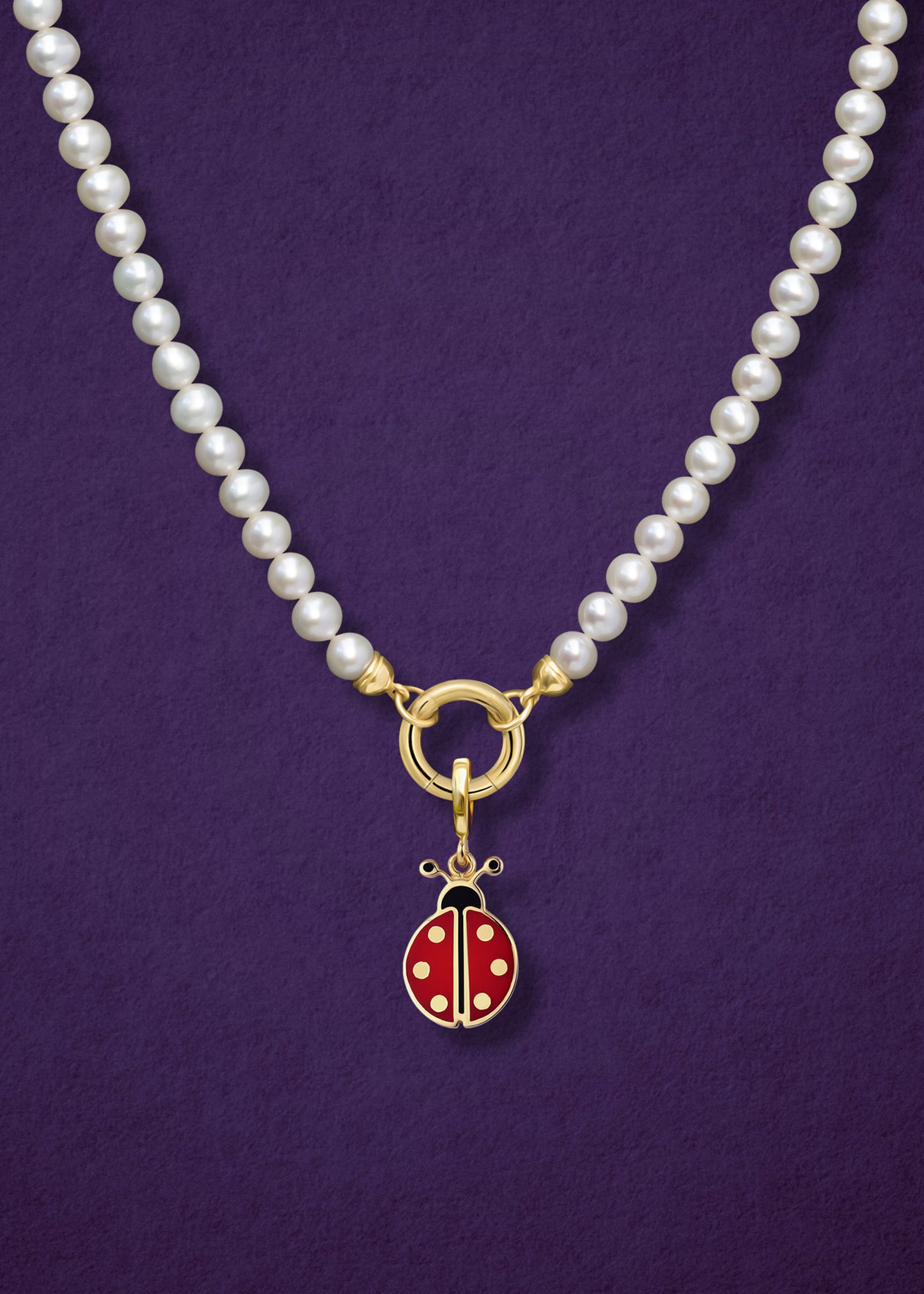 Close-up of the Lustrous Pearl Charm Necklace paired with the Lucky Ladybird Charm by whywhy NYC, showcasing freshwater pearls and 14K solid gold with vibrant enamel for a playful, elegant style.