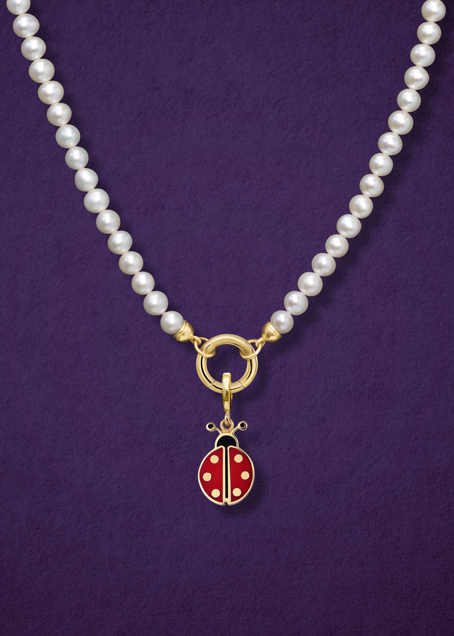Close-up of the Lustrous Pearl Charm Necklace paired with the Lucky Ladybird Charm by whywhy NYC, showcasing freshwater pearls and 14K solid gold with vibrant enamel for a playful, elegant style.