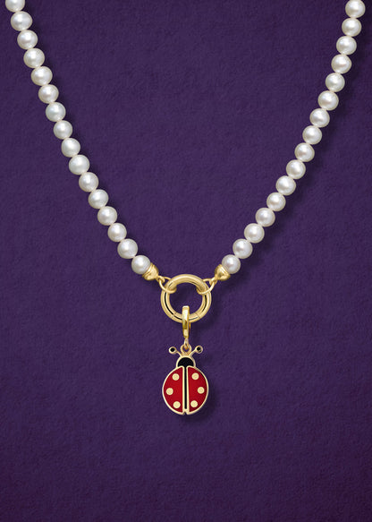 Close-up of the Lustrous Pearl Charm Necklace paired with the Lucky Ladybird Charm by whywhy NYC, showcasing freshwater pearls and 14K solid gold with vibrant enamel for a playful, elegant style.