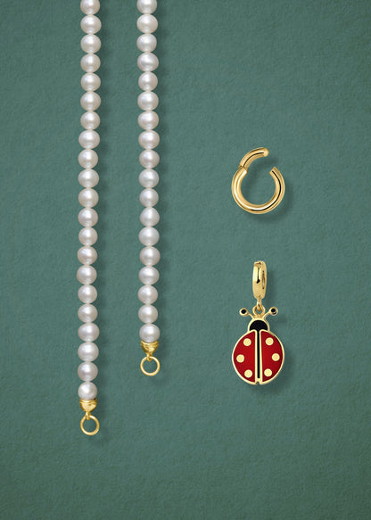 Close-up of the separated Lustrous Pearl Lucky Ladybird Charm Necklace components: pearl necklace, golden link charm holder, and lucky ladybird charm in 14K solid gold by whywhy NYC.