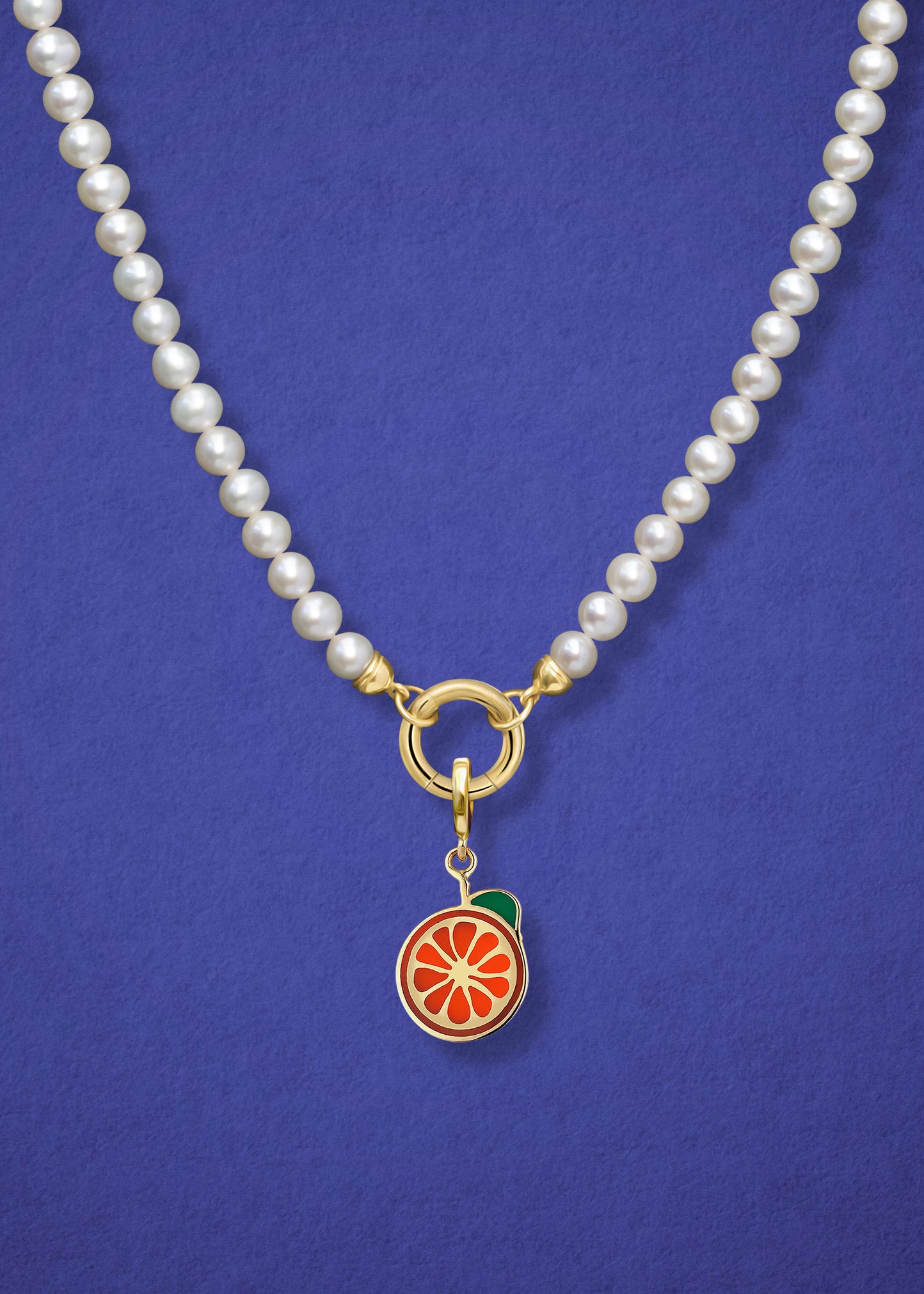 Close-up of the Lustrous Pearl Orange Crush Charm Necklace, featuring freshwater pearls, a golden link charm holder, and an orange crush charm in 14K solid gold by whywhy NYC.
