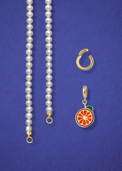 Close-up of the separated Lustrous Pearl Orange Crush Charm Necklace components: pearl necklace, golden link charm holder, and orange crush charm in 14K solid gold by whywhy NYC.