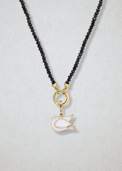 Close-up of the Noir Elegance Dove of Hope Charm Necklace, featuring faceted black spinel beads, a golden link charm holder, and a dove of hope charm with white enamel by whywhy NYC