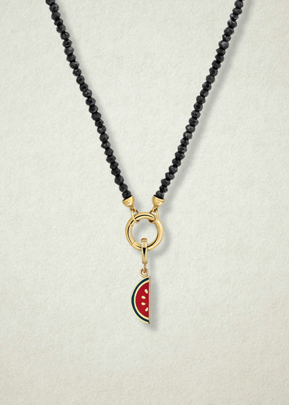 Close-up of the Noir Elegance Watermelon Wonder Charm Necklace, featuring faceted black spinel beads, a golden link charm holder, and a watermelon wonder charm with pink and green enamel by whywhy NYC.