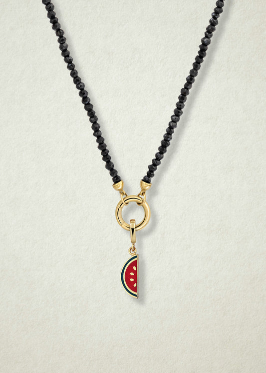 Close-up of the Noir Elegance Watermelon Wonder Charm Necklace, featuring faceted black spinel beads, a golden link charm holder, and a watermelon wonder charm with pink and green enamel by whywhy NYC.
