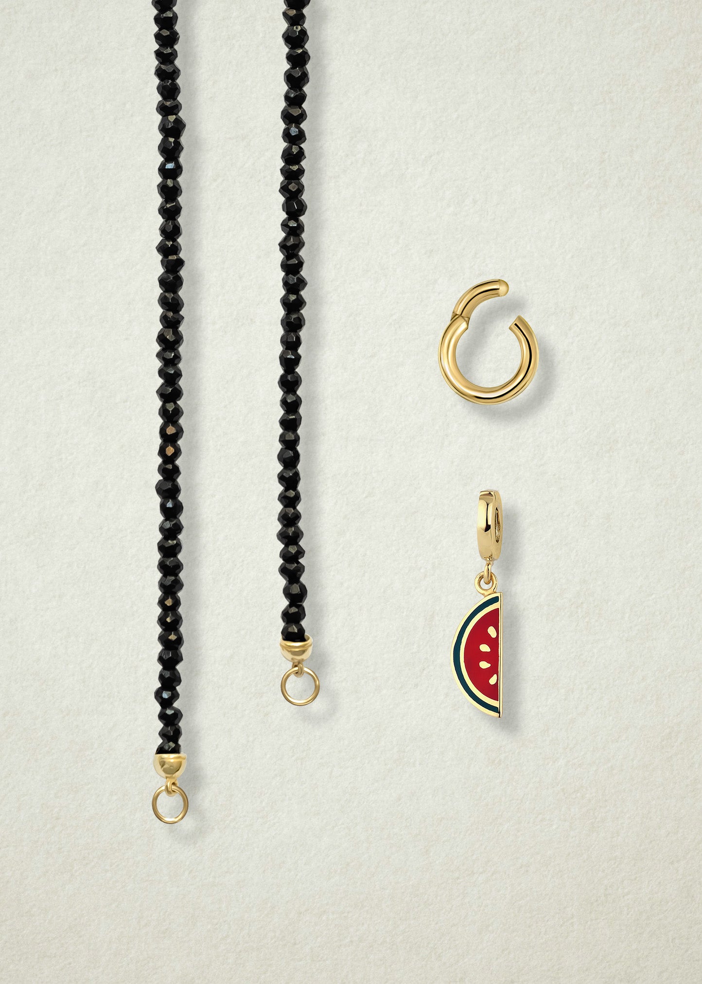 Close-up of the separated Noir Elegance Watermelon Wonder Charm Necklace components: black spinel necklace, golden link charm holder, and watermelon wonder charm with pink and green enamel by whywhy NYC.