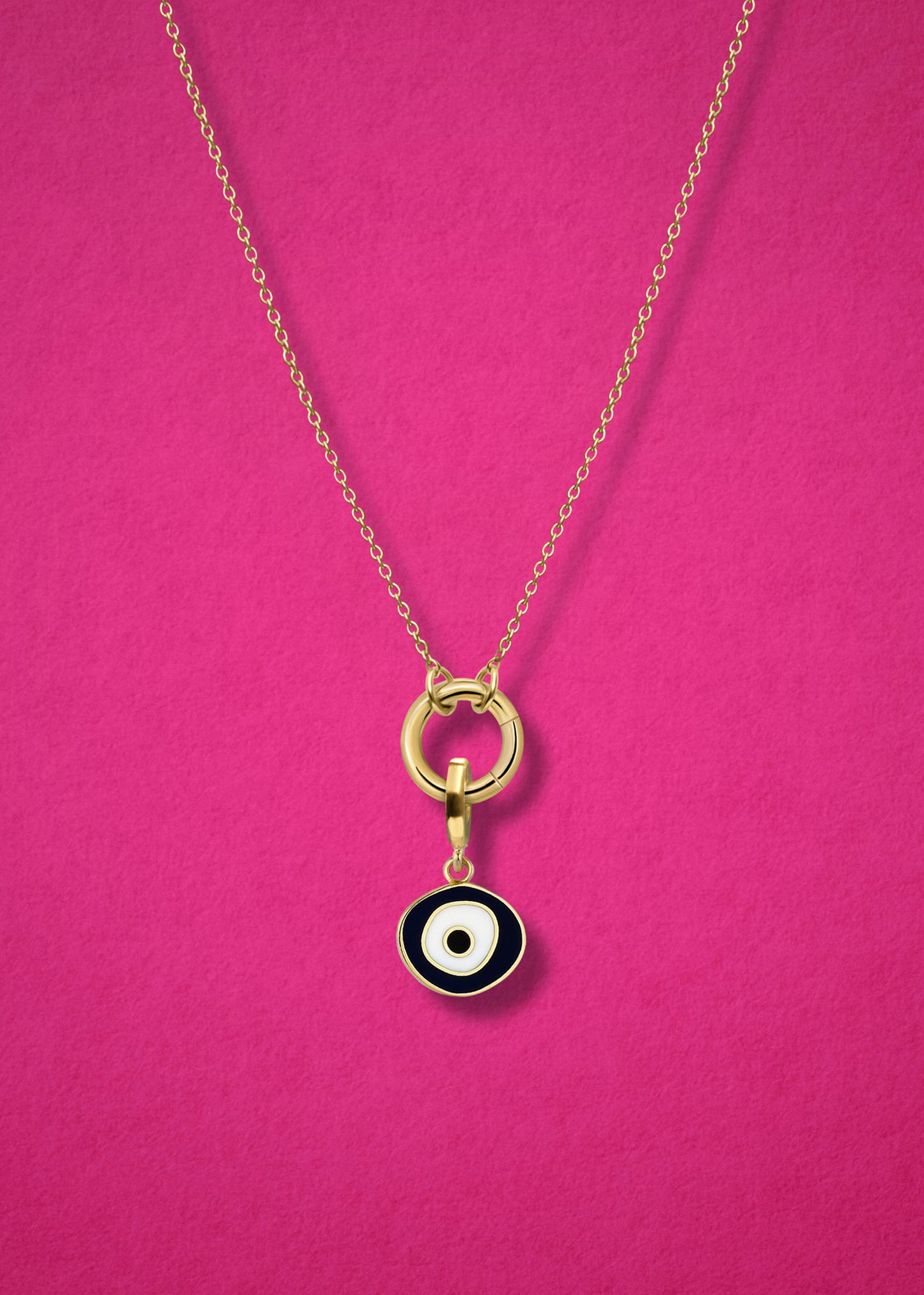 Close-up of the Obsidian Organic Evil Eye Charm with hand-painted enamel on a 14K solid gold cable chain necklace, shown on a magenta background.