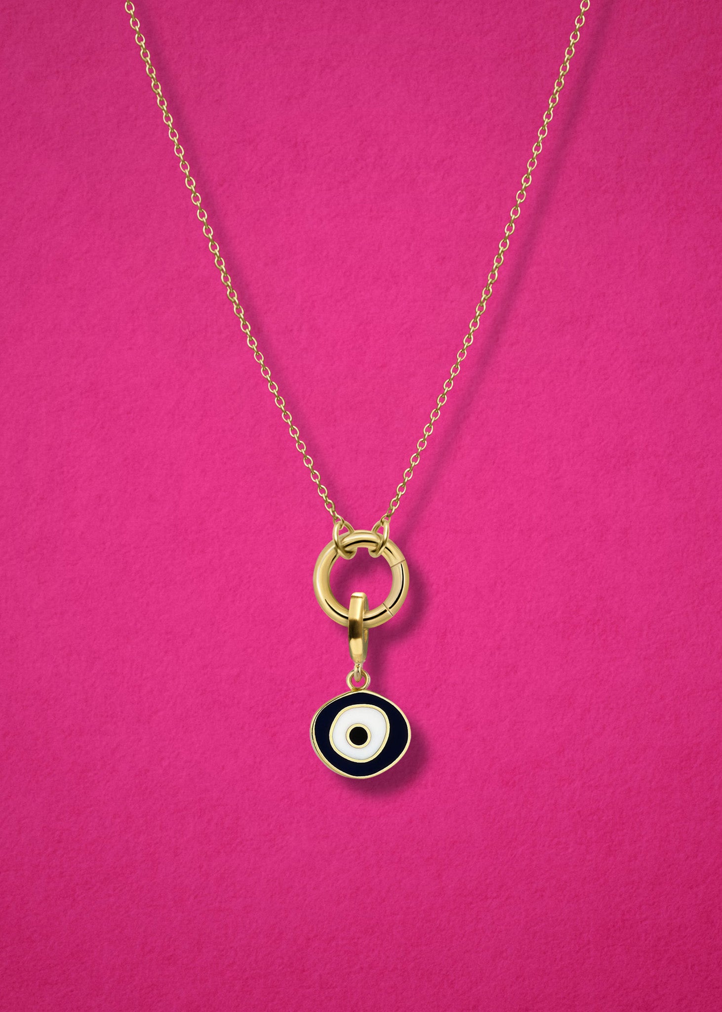 Close-up of the Obsidian Organic Evil Eye Charm with hand-painted enamel on a 14K solid gold cable chain necklace, shown on a magenta background.