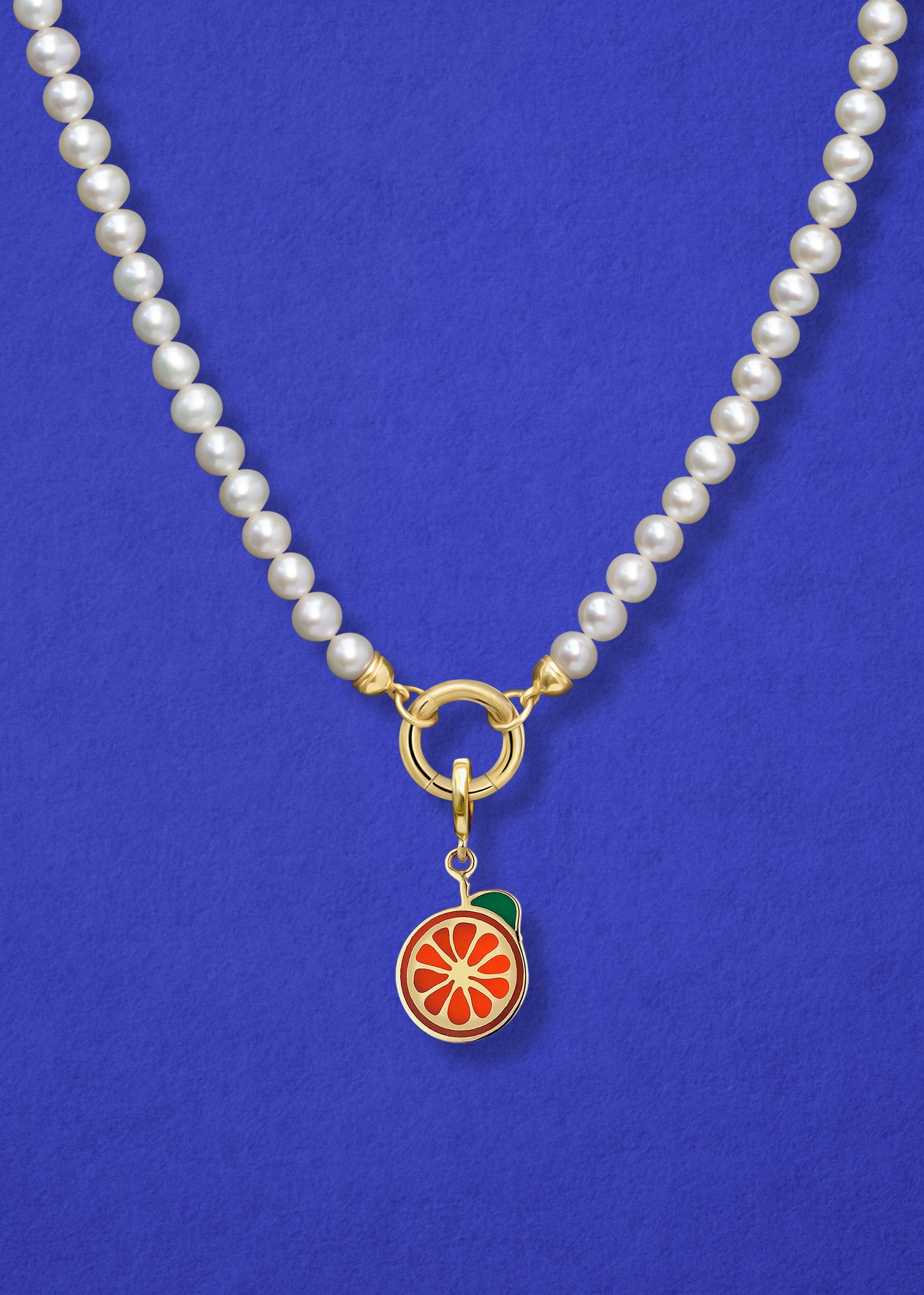 Close-up of the Orange Crush Charm paired with the Lustrous Pearl Charm Necklace by whywhy NYC, featuring 14K solid gold and freshwater pearls for a timeless yet playful look.