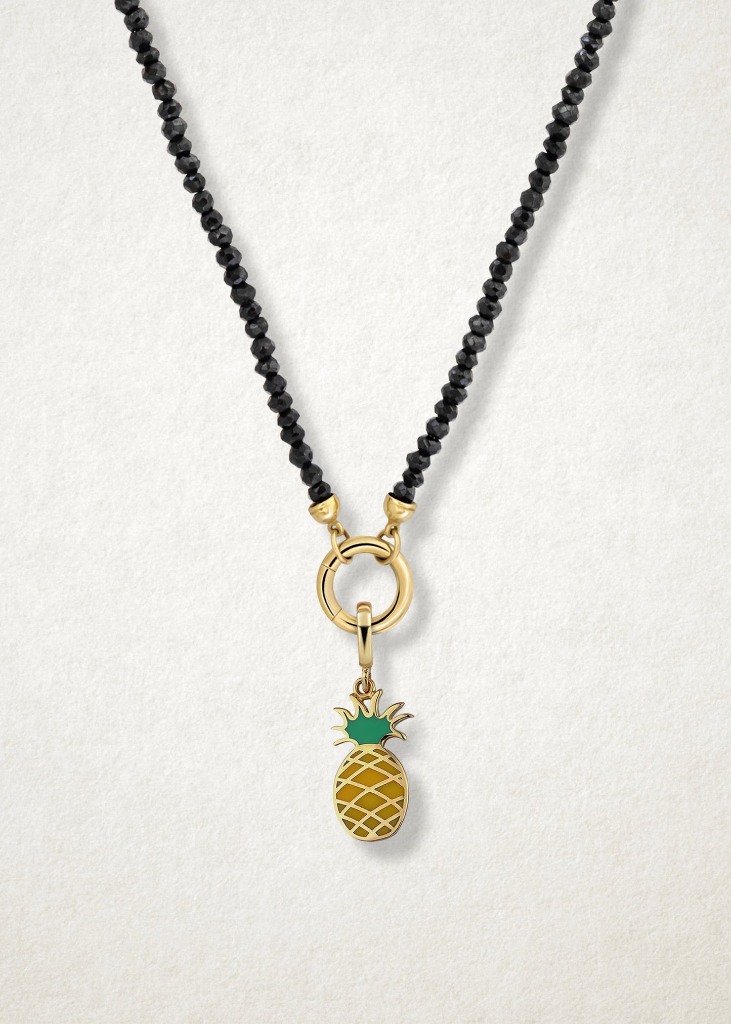 Close-up of the Pineapple Paradise Charm paired with the Noir Elegance Charm Necklace by whywhy NYC, featuring black spinel and 14K solid gold for a bold and tropical-inspired design.