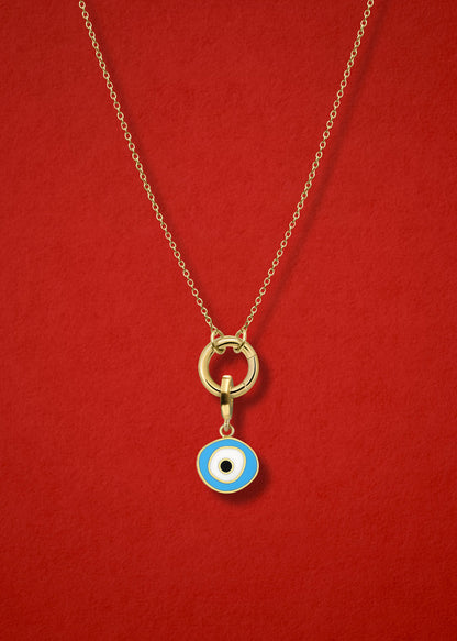 Close-up of the Sky Organic Evil Eye Charm with hand-painted enamel on a 14K solid gold cable chain necklace, shown on a red background.