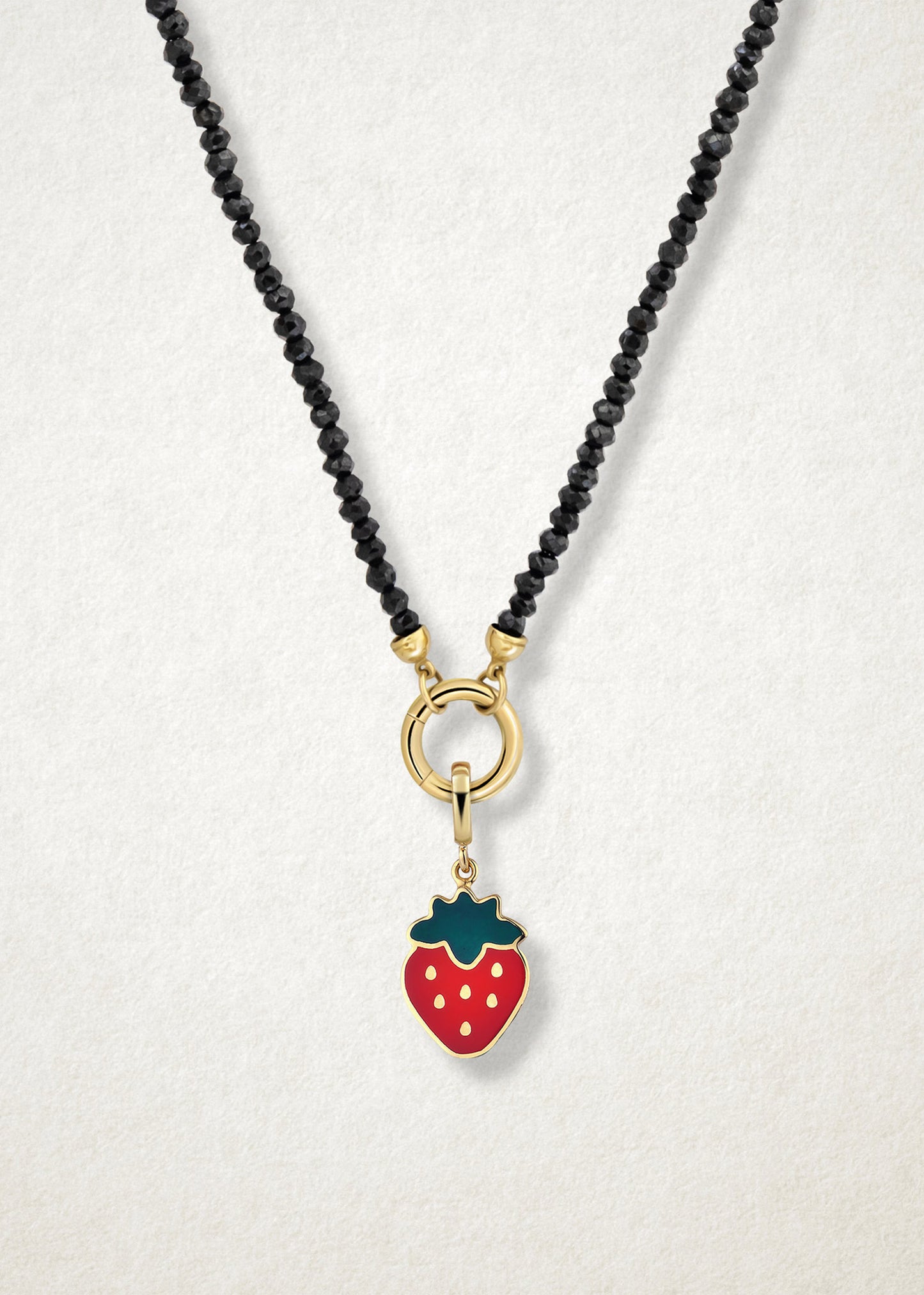 Close-up of the Sweet Strawberry Delight Charm paired with the Noir Elegance Charm Necklace by whywhy NYC, featuring black spinel and 14K solid gold for a bold and sweet combination.