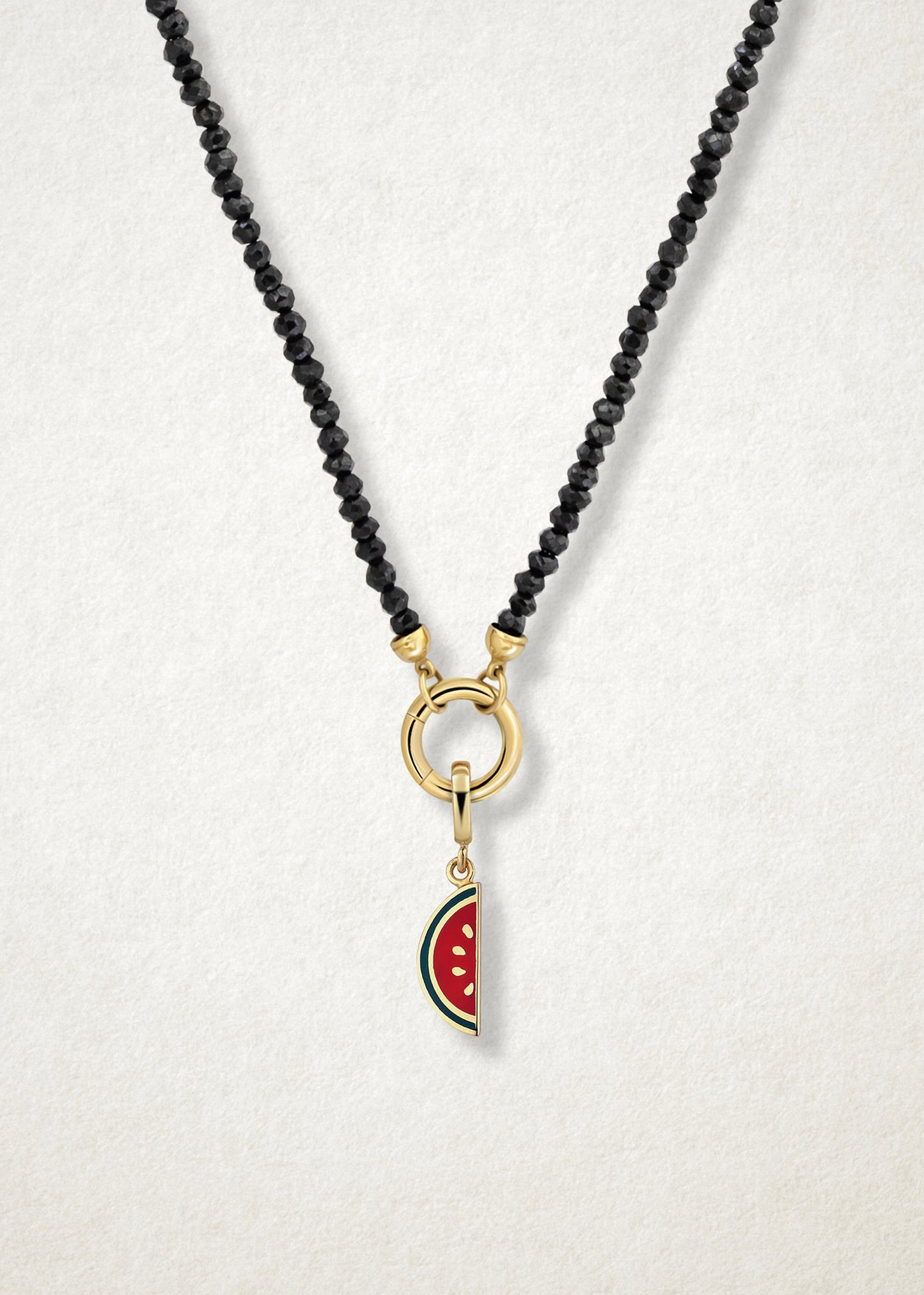 Close-up of the Watermelon Wonder Charm paired with the Noir Elegance Charm Necklace by whywhy NYC, featuring black spinel and 14K solid gold for a bold and unique statement.