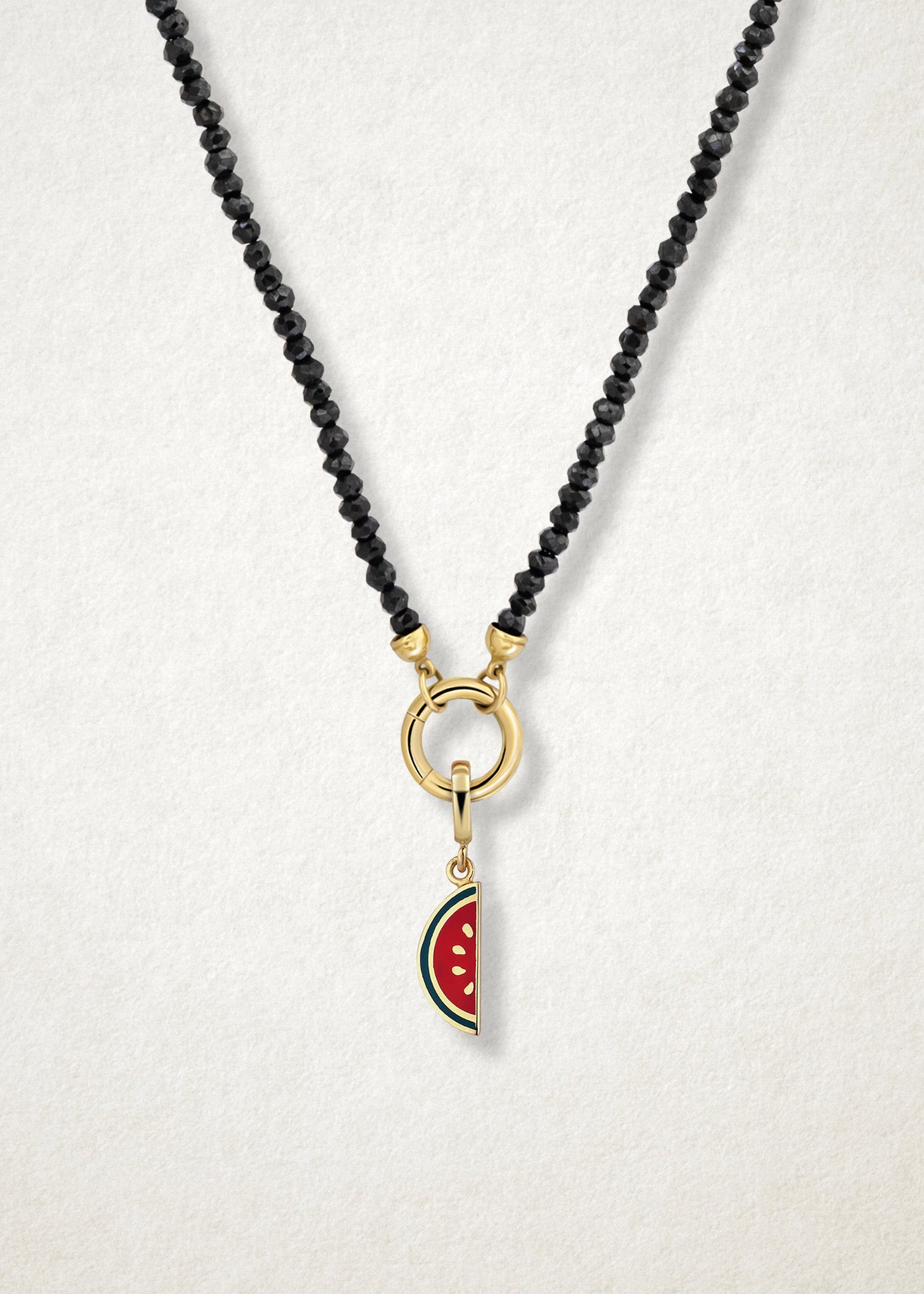 Close-up of the Watermelon Wonder Charm paired with the Noir Elegance Charm Necklace by whywhy NYC, featuring black spinel and 14K solid gold for a bold and unique statement.
