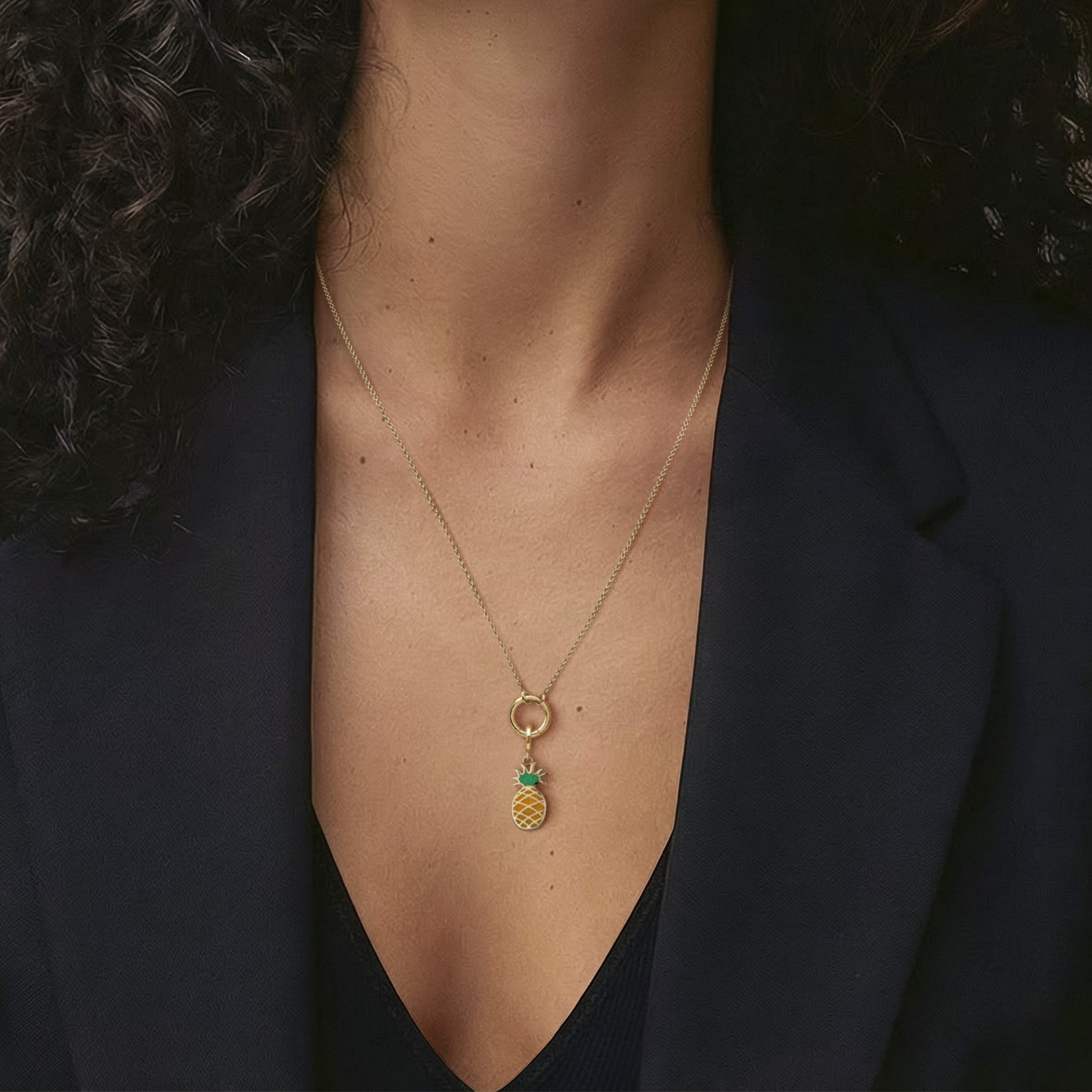 Close-up neckline view of the Golden Grace Pineapple Paradise Charm Necklace with a 14K solid gold cable chain, charm holder, and yellow and green enamel pineapple charm.