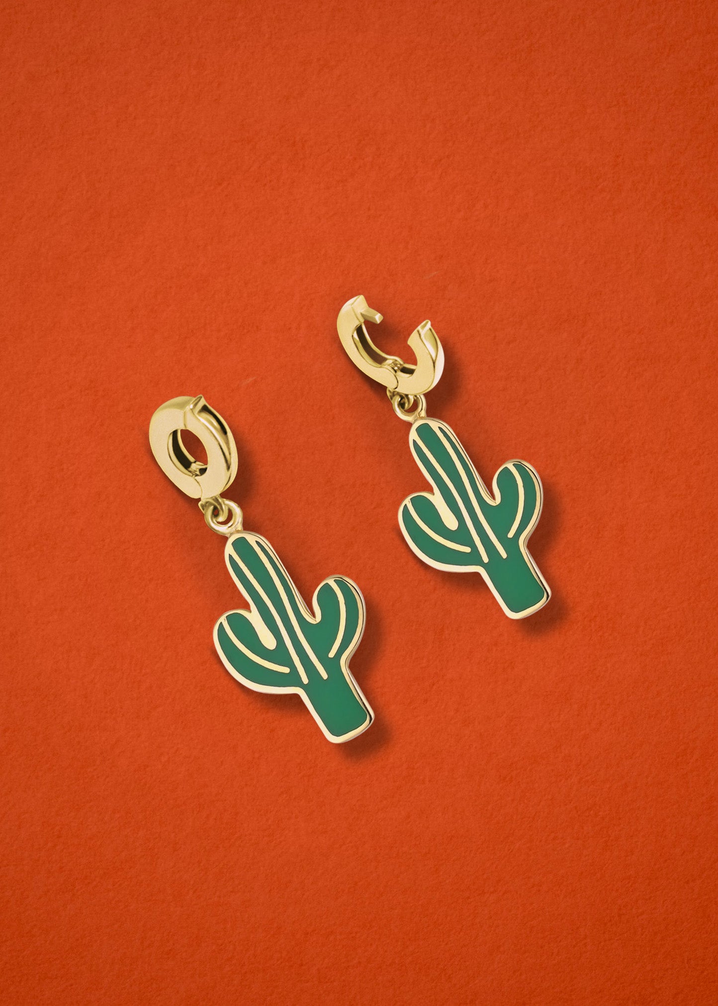 Desert Bloom Charm showing both open and closed views of the 14K solid gold clip, featuring lush green enamel accents, displayed on an orange background.