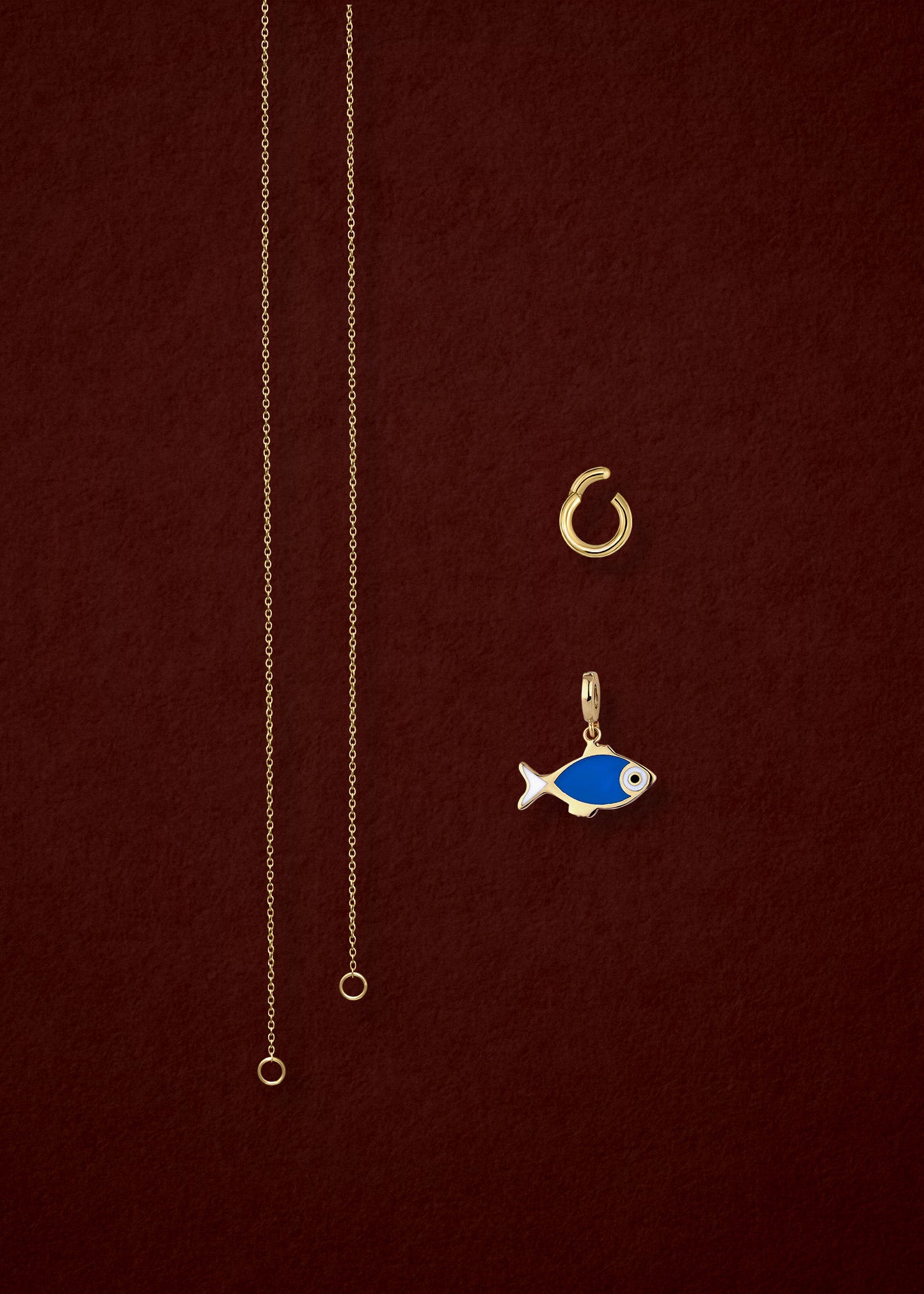 Separated components of the Golden Grace Fishy Wishes Charm Necklace, including 14K solid gold cable chain, golden charm holder, and fishy wishes charm with vibrant enamel by whywhy NYC.