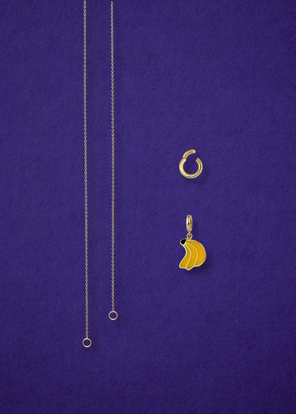 Separated components of the Golden Grace Banana Bliss Charm Necklace, including 14K solid gold cable chain, golden link charm holder, and banana bliss charm with yellow enamel by whywhy NYC.