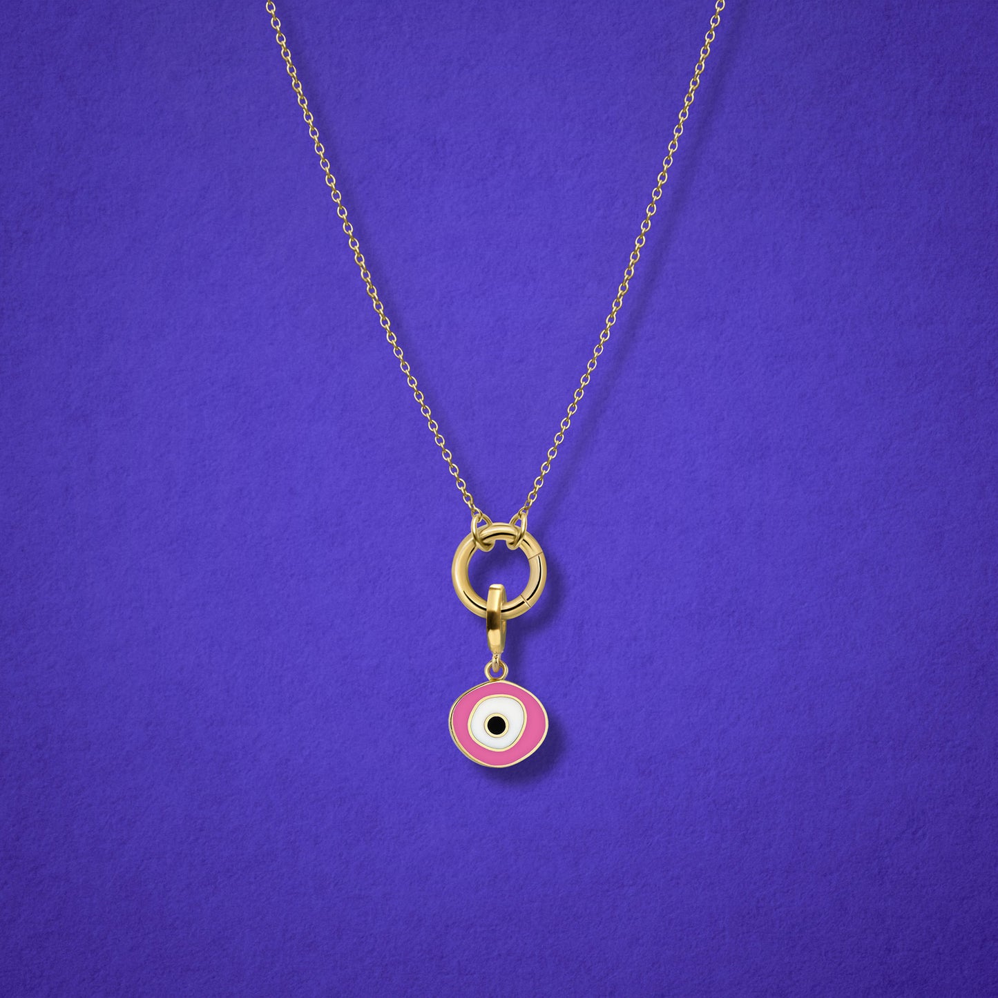 Close-up of the Blush Organic Evil Eye Charm with hand-painted enamel on a 14K solid gold cable chain necklace, shown on a lilac background.