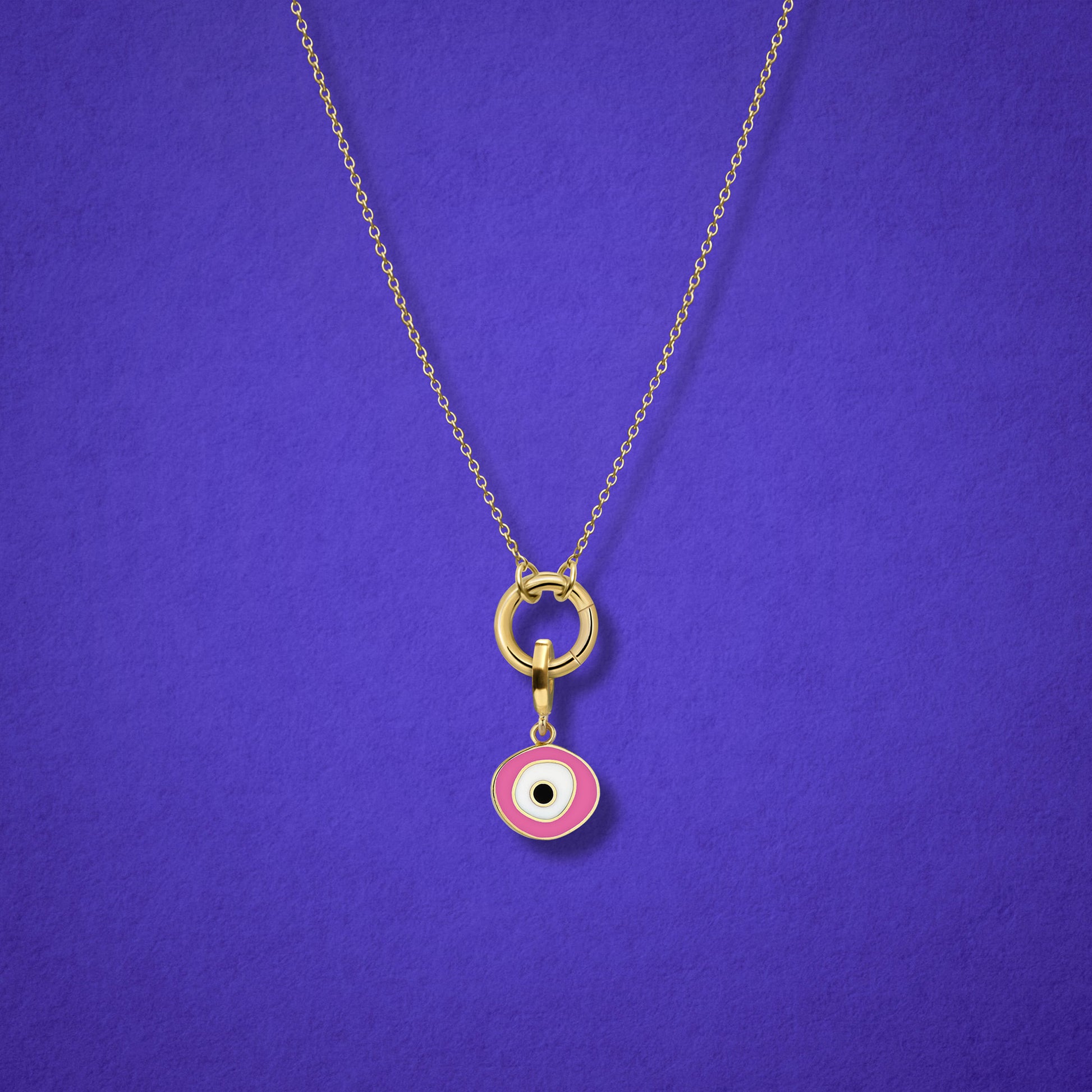Close-up of the Blush Organic Evil Eye Charm with hand-painted enamel on a 14K solid gold cable chain necklace, shown on a lilac background.