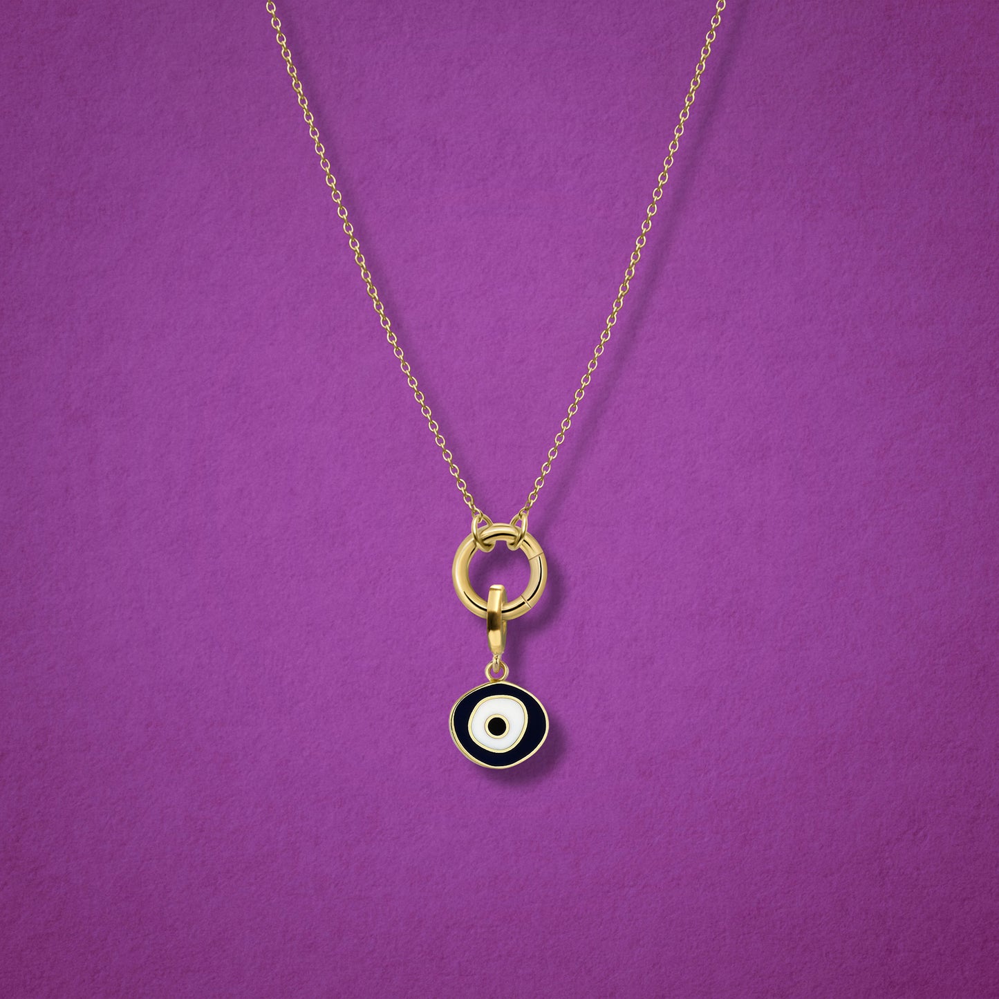 Close-up of the Obsidian Organic Evil Eye Charm with hand-painted enamel on a 14K solid gold cable chain necklace, shown on a magenta background.