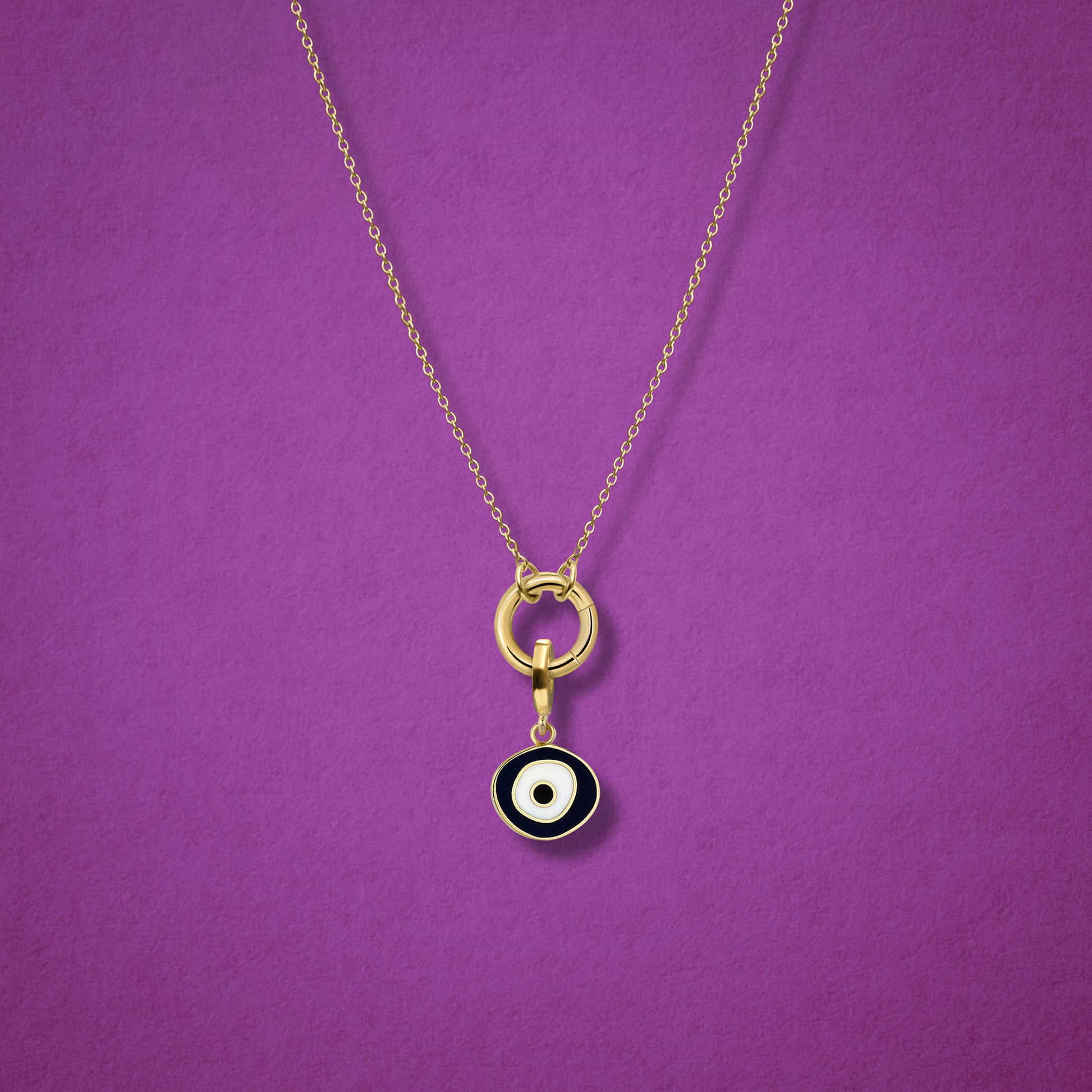 Close-up of the Obsidian Organic Evil Eye Charm with hand-painted enamel on a 14K solid gold cable chain necklace, shown on a magenta background.