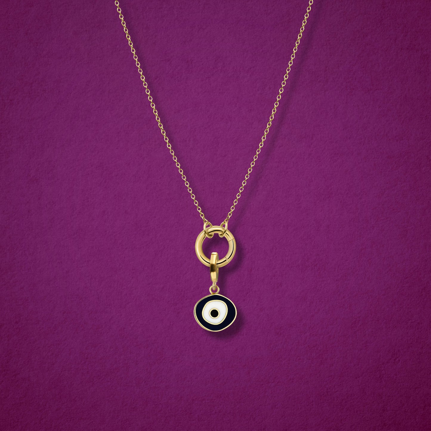 Close-up of the Obsidian Organic Evil Eye Charm with hand-painted enamel on a 14K solid gold cable chain necklace, shown on a magenta background.