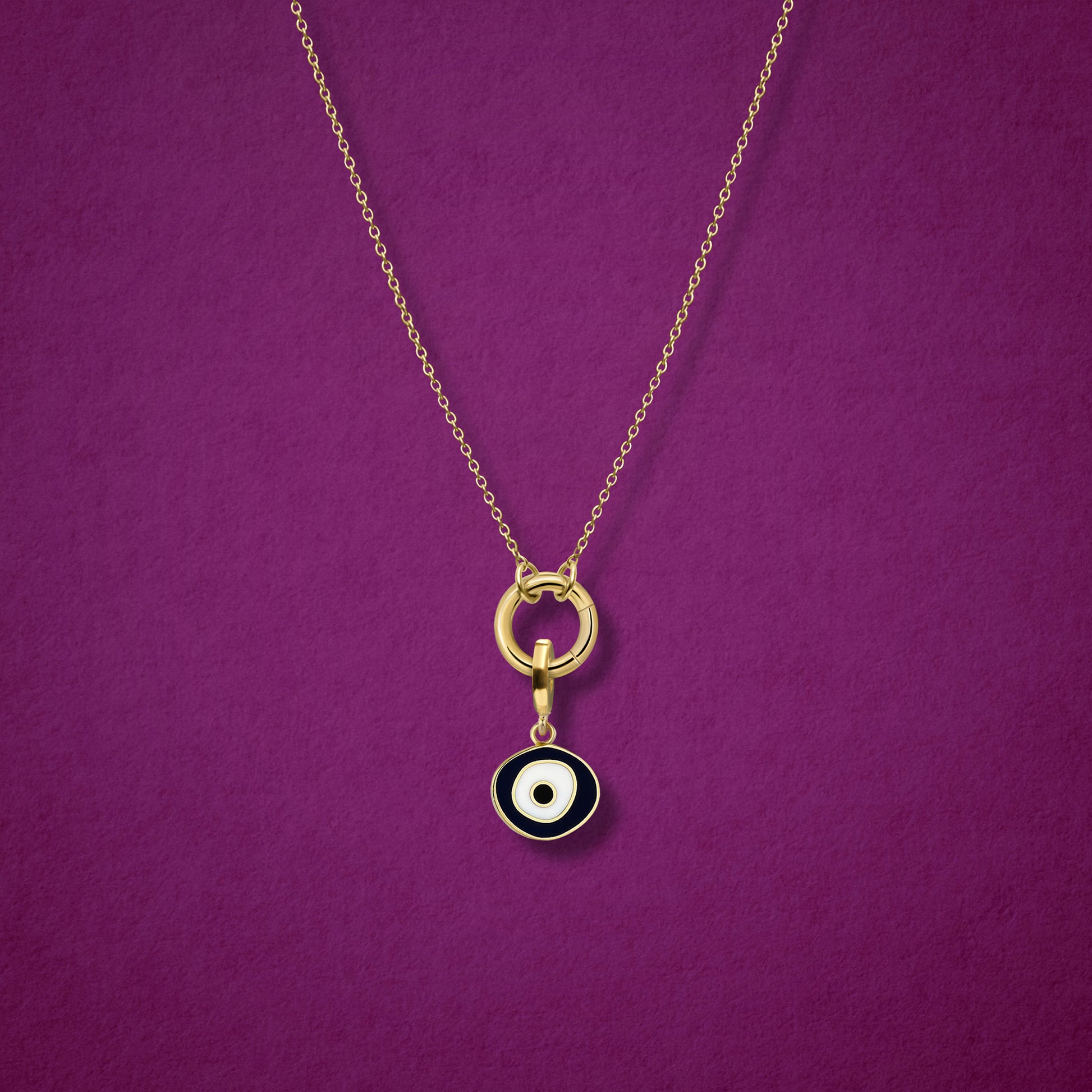 Close-up of the Obsidian Organic Evil Eye Charm with hand-painted enamel on a 14K solid gold cable chain necklace, shown on a magenta background.