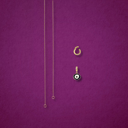 Obsidian Organic Evil Eye Charm, Golden Link Charm Holder, and the Golden Grace cable chain necklace displayed separately on a magenta background to show styling options.