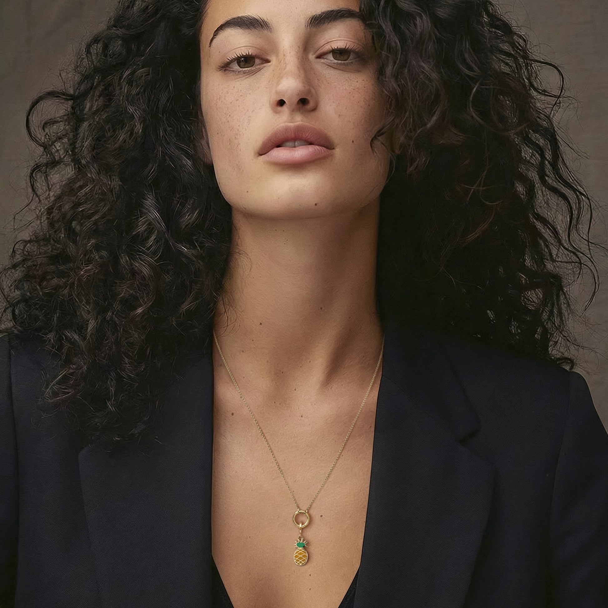 Model wearing the Golden Grace Pineapple Paradise Charm Necklace, featuring a 20-inch 1.5mm cable chain, an 11mm outer diameter, a 1.5mm thick 14K solid gold charm holder, and a green and yellow enamel pineapple charm crafted in 14K solid gold.