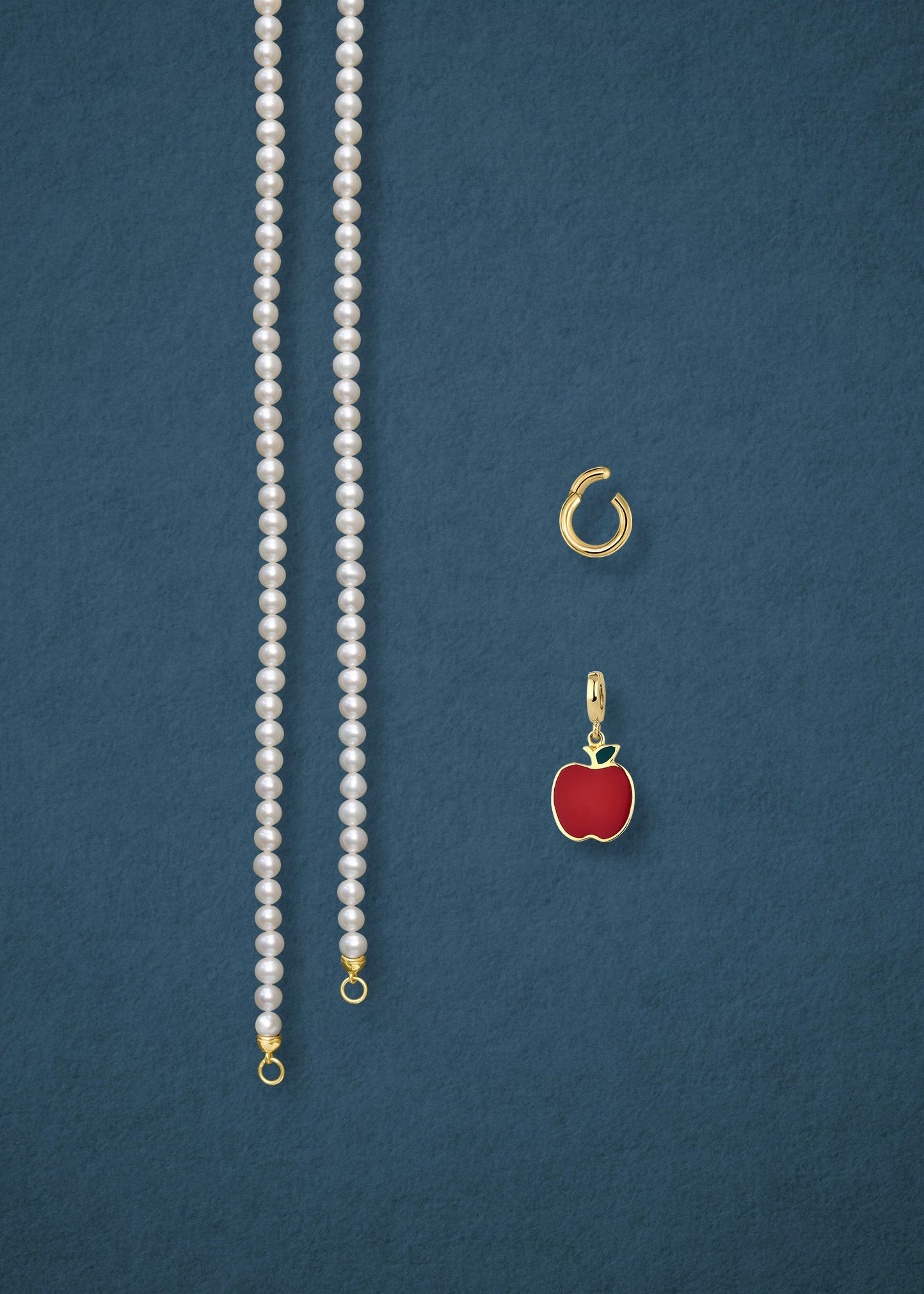 Separated components of the Lustrous Pearl Golden Apple of NYC Charm Necklace, including pearl necklace, charm holder, and golden apple charm in 14K solid gold by whywhy NYC.